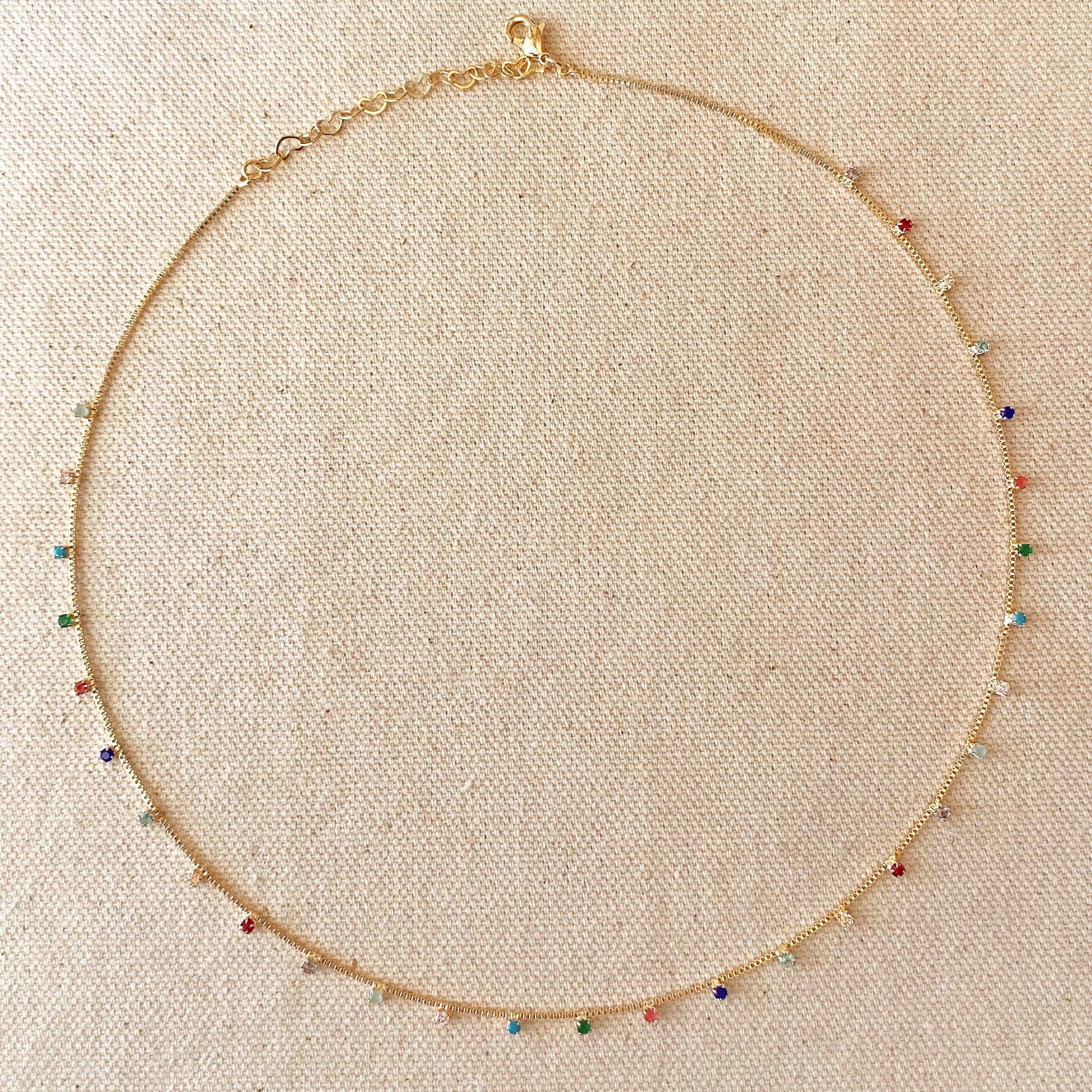 Gold necklace with colorful beads on a beige fabric background