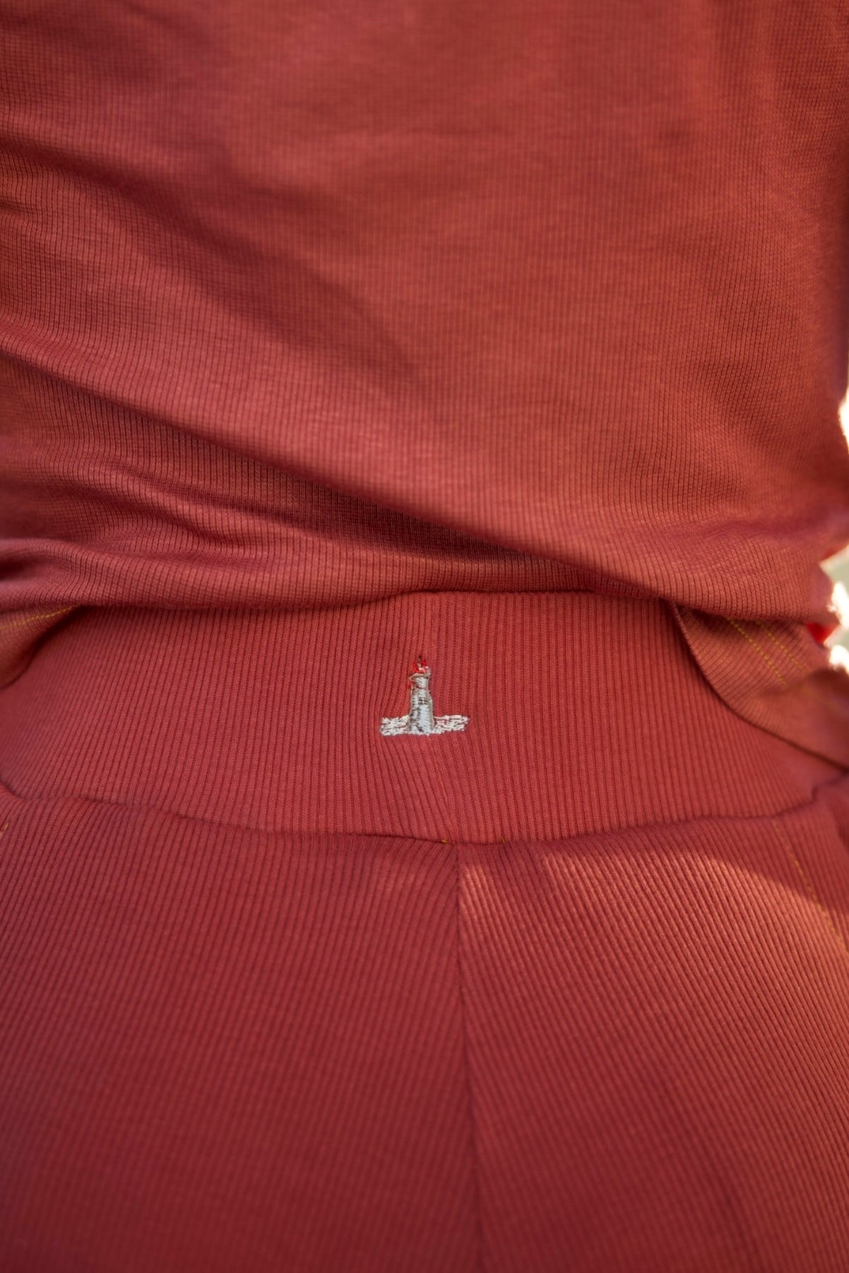 Close-up of a red garment with a small embroidered logo on a blurred background