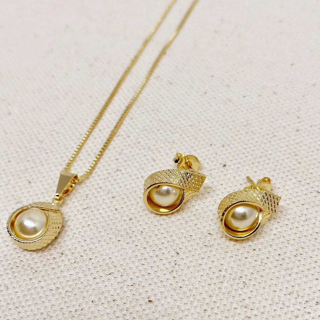 Gold necklace and earrings with pearl-like centers on a textured beige background