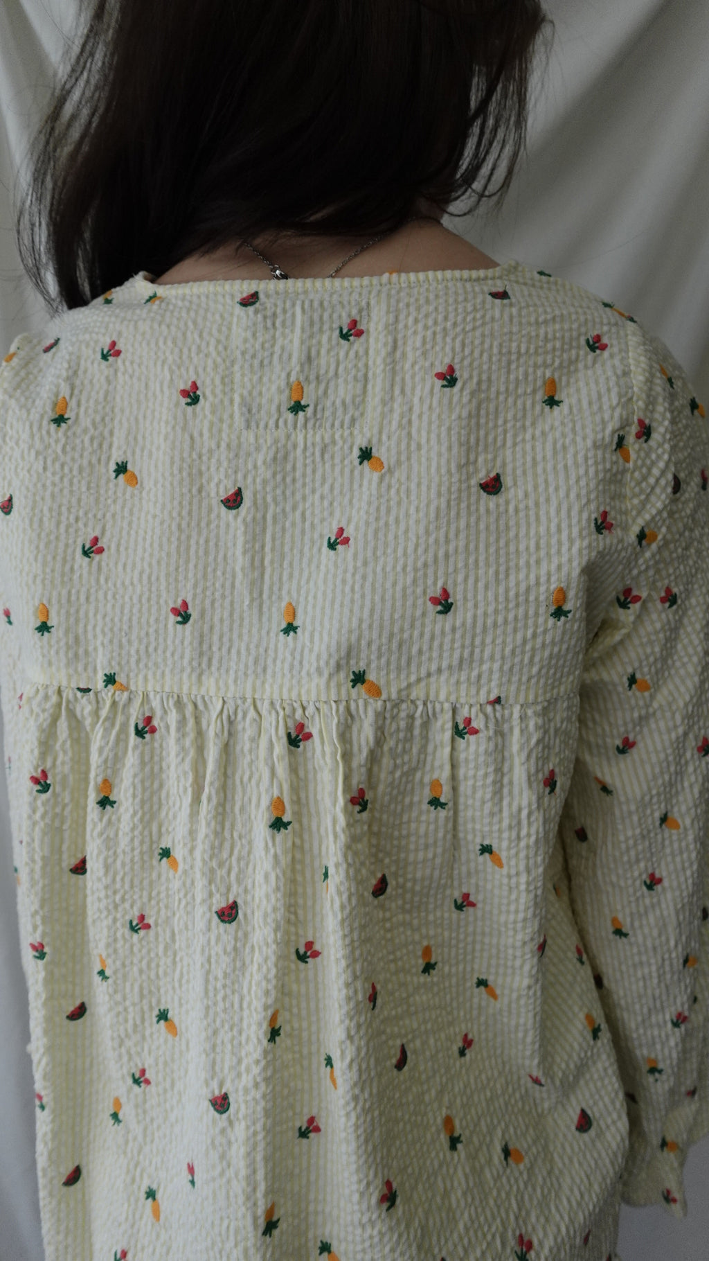 Person lying under a patterned quilt with small colorful designs on a plain background