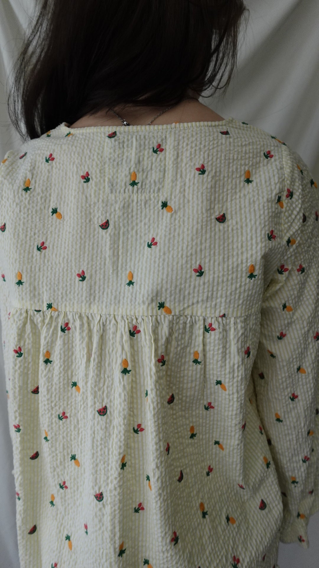 Person lying under a patterned quilt with small colorful designs on a plain background