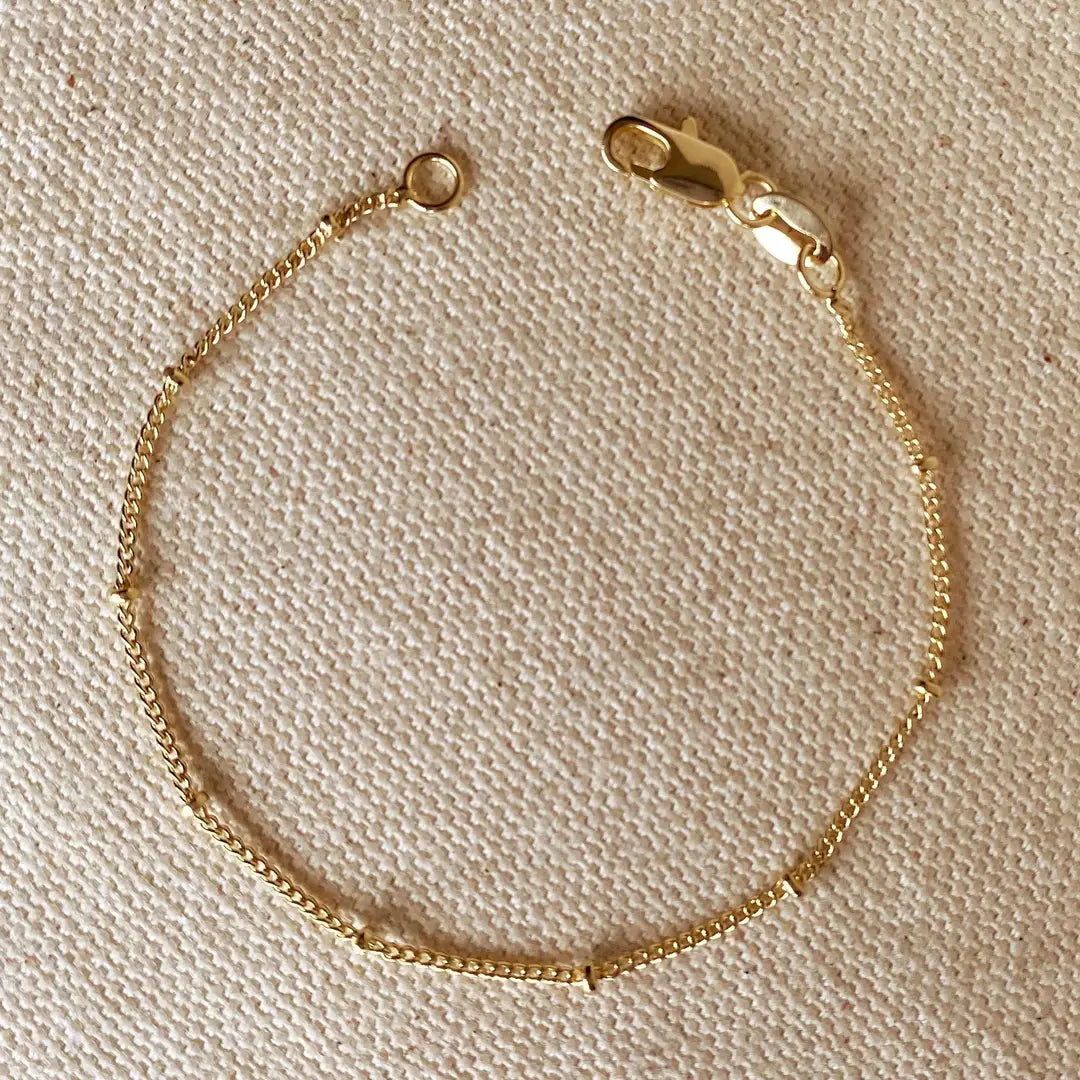 Gold bracelet on a beige textured background