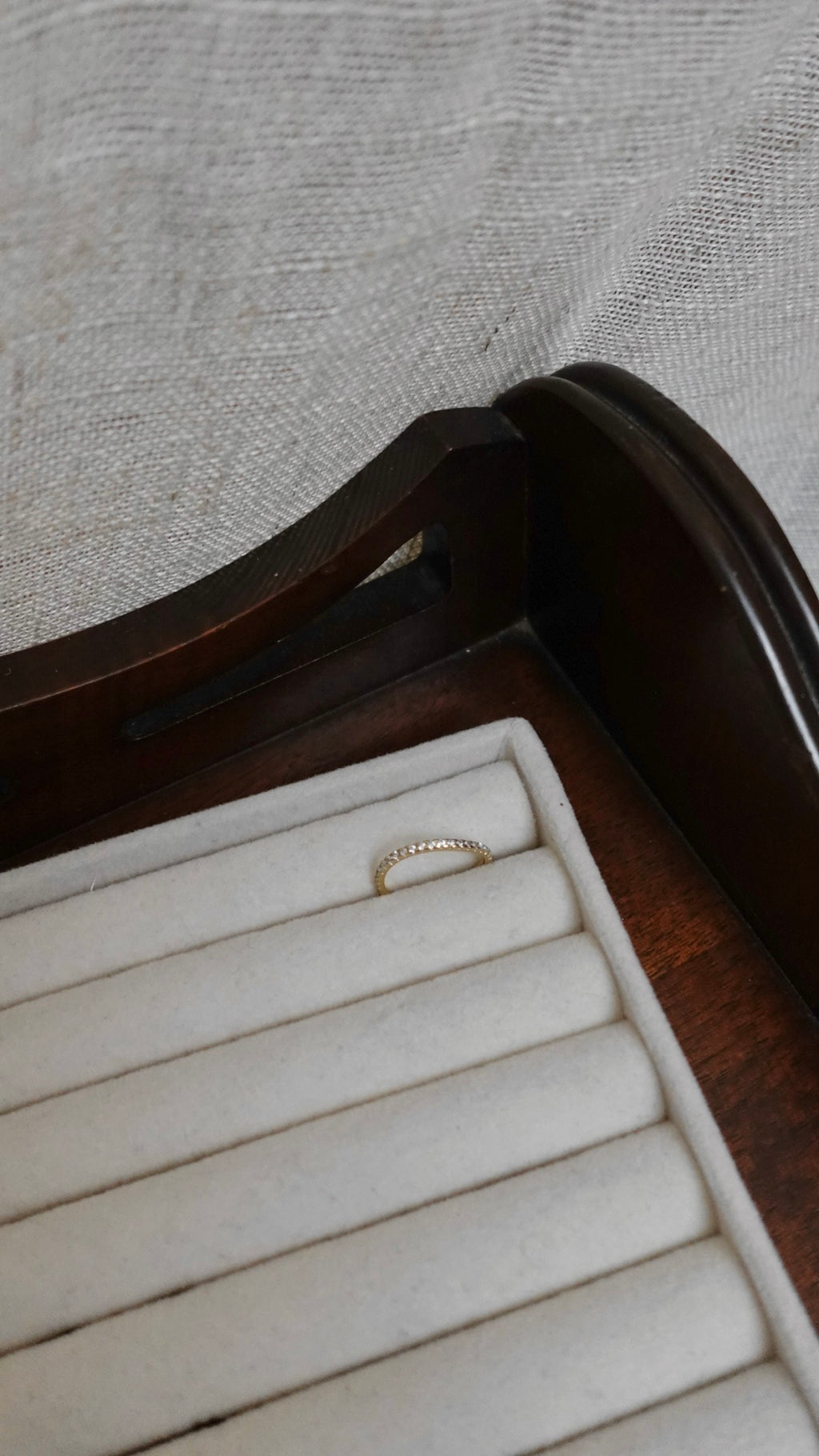 Gold ring on a wooden jewelry box with a gray fabric background