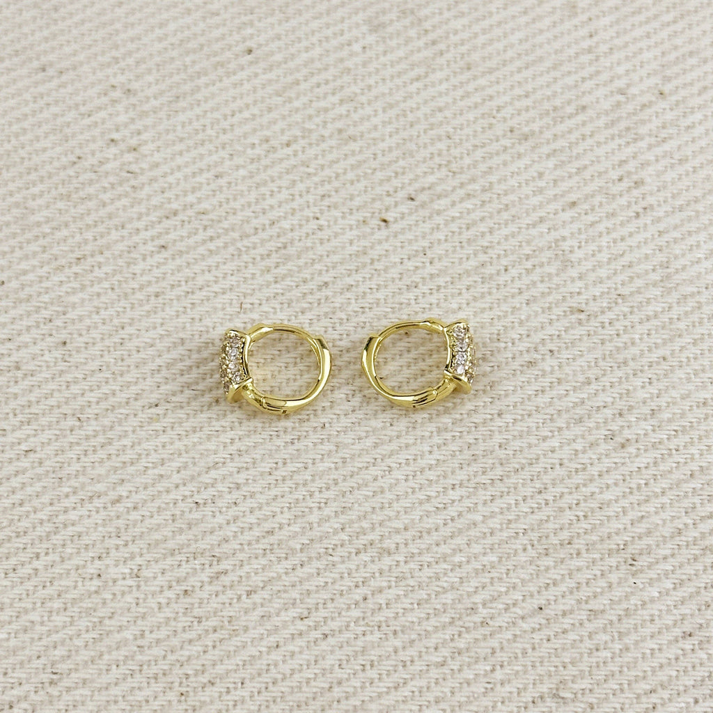 Gold hoop earrings with small diamonds on a beige fabric background