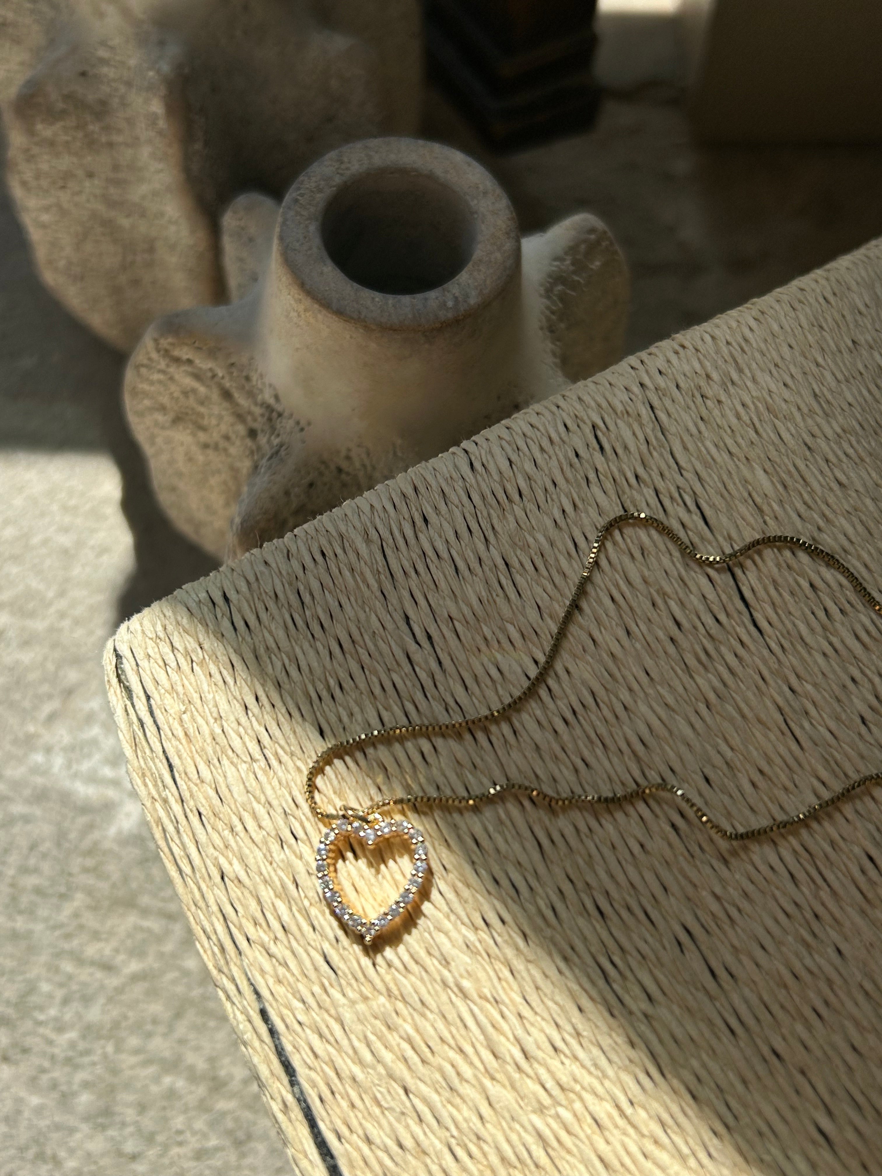 Gold necklace on a textured beige surface