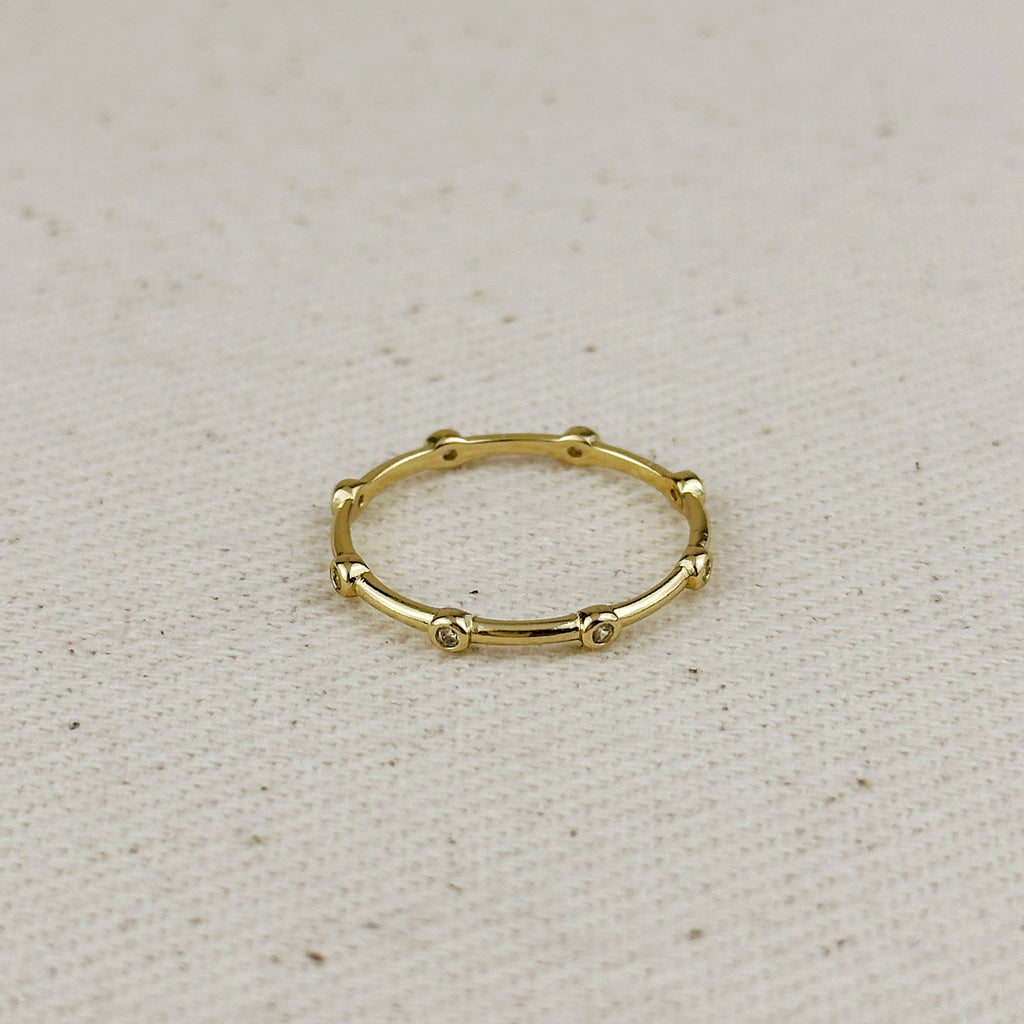 Gold ring with small beads on a beige fabric background