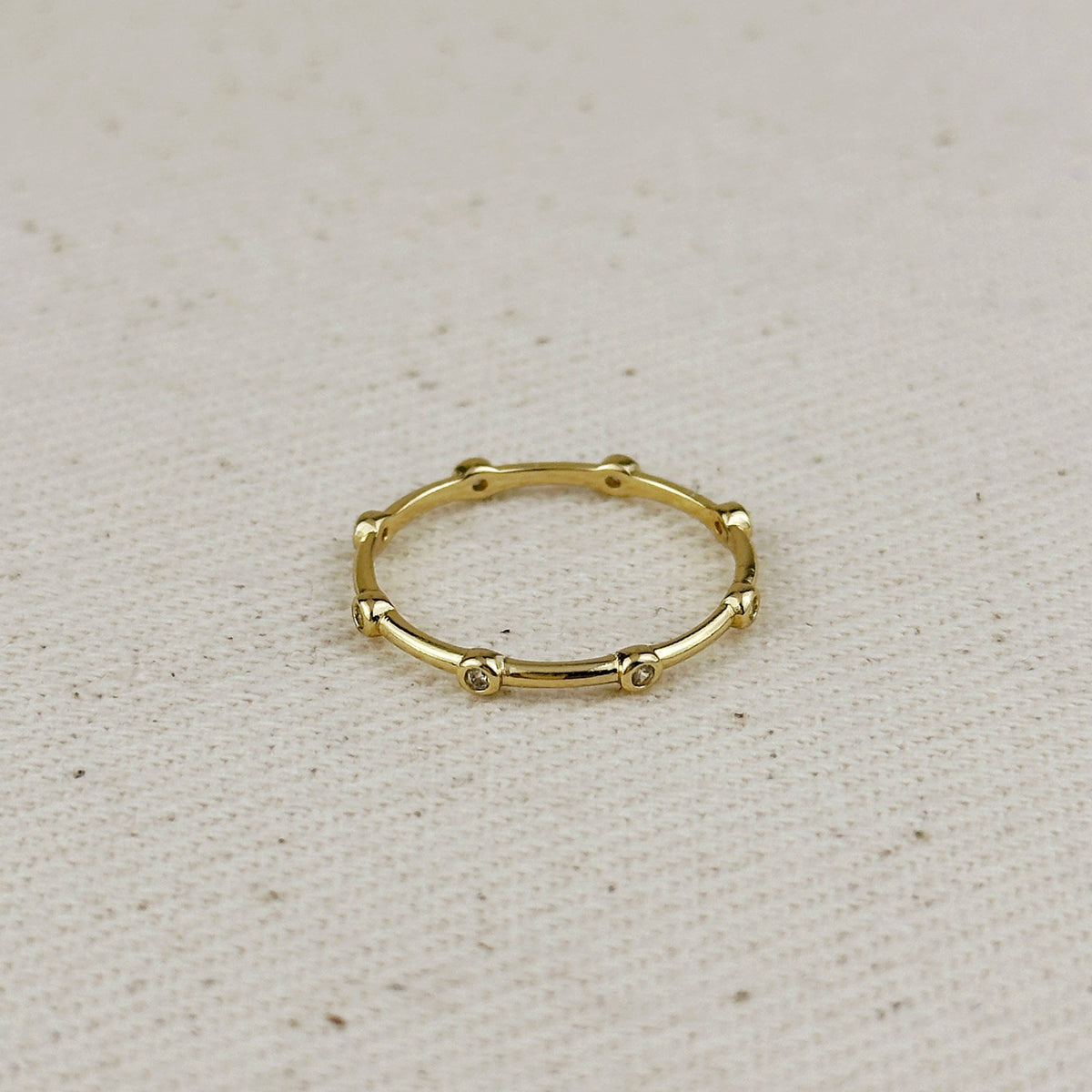 Gold ring with small beads on a beige fabric background