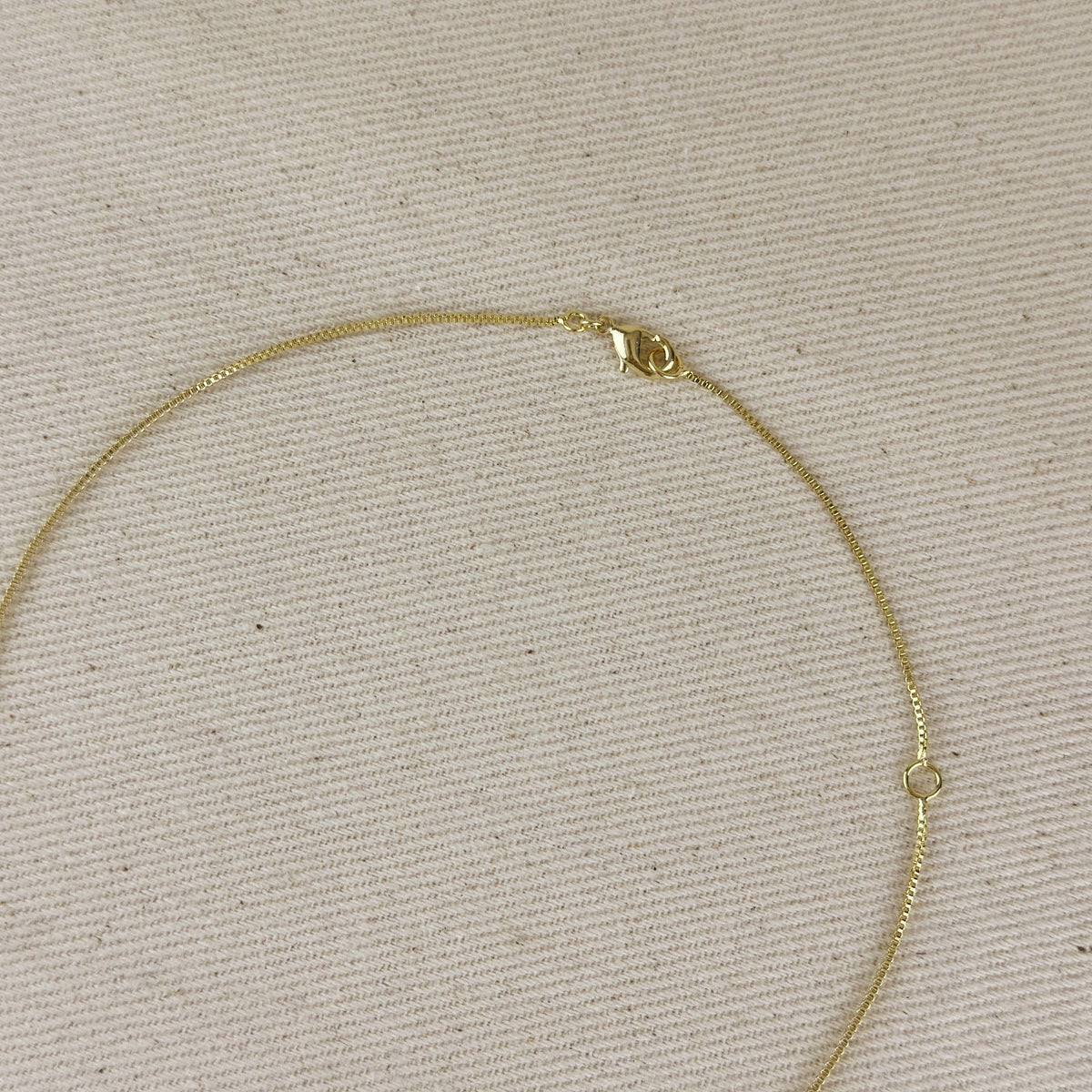 Gold necklace on a beige textured background