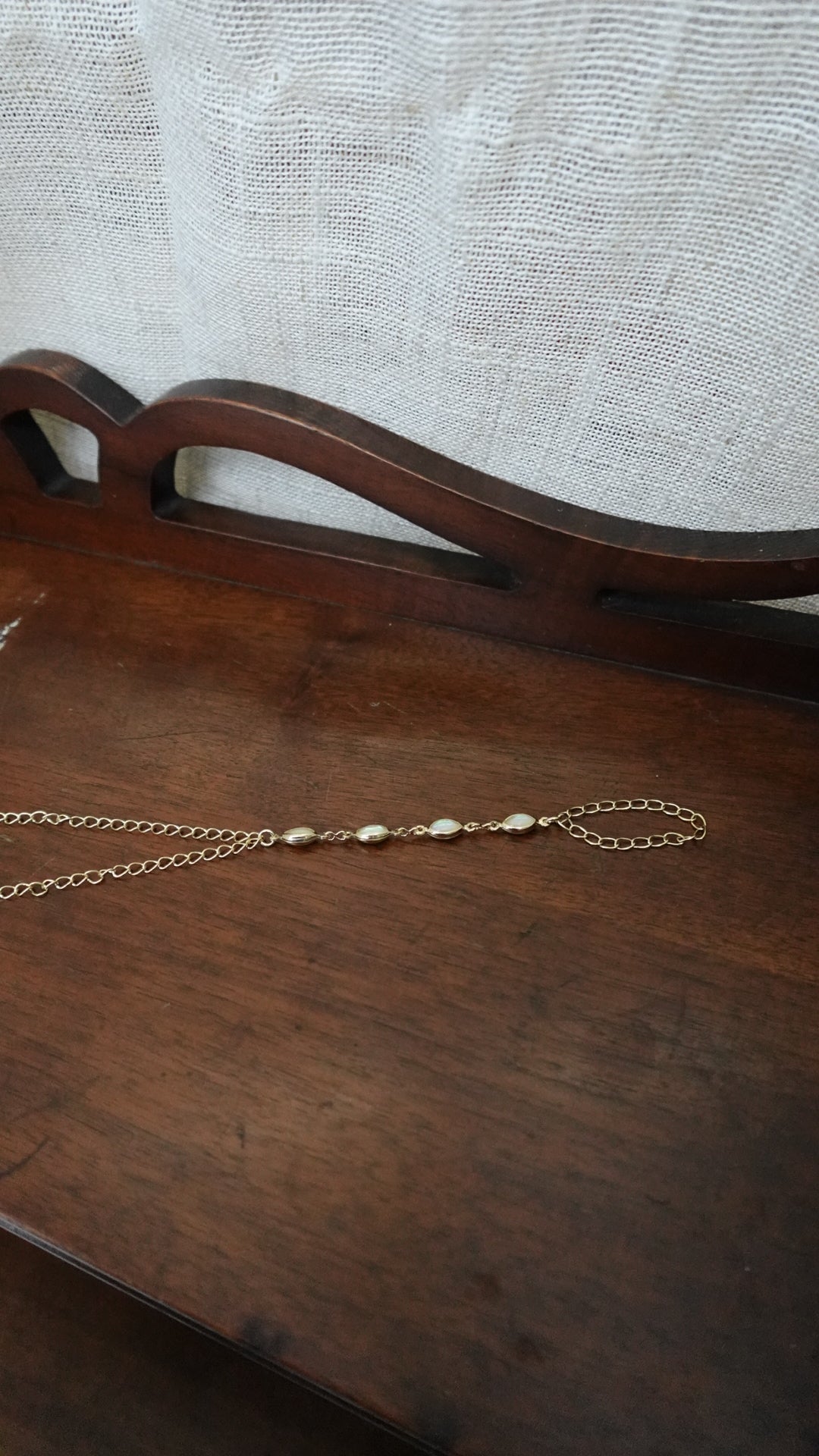 Pearl necklace on a wooden surface with a textured fabric background