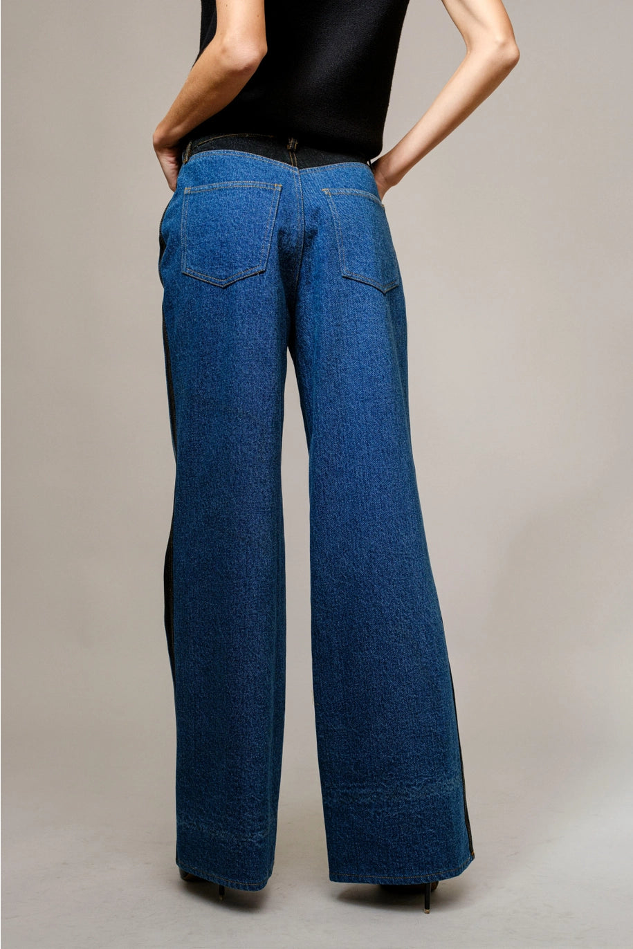 Person wearing blue denim wide-leg pants on a plain background