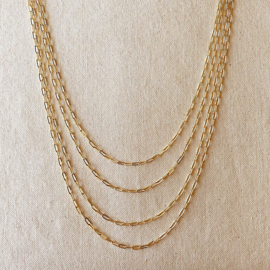 Set of gold chain necklaces on a beige fabric background