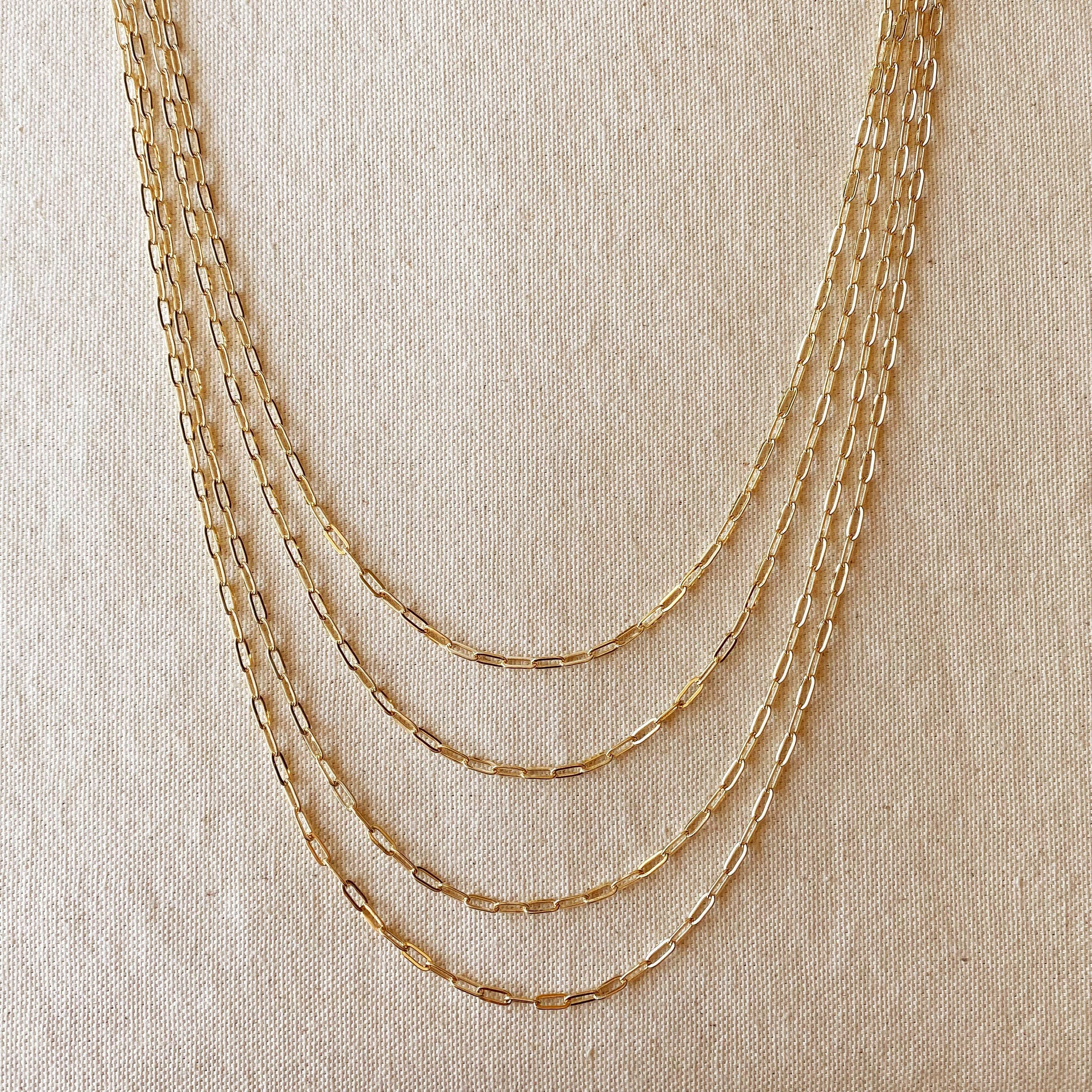 Set of gold chain necklaces on a beige fabric background