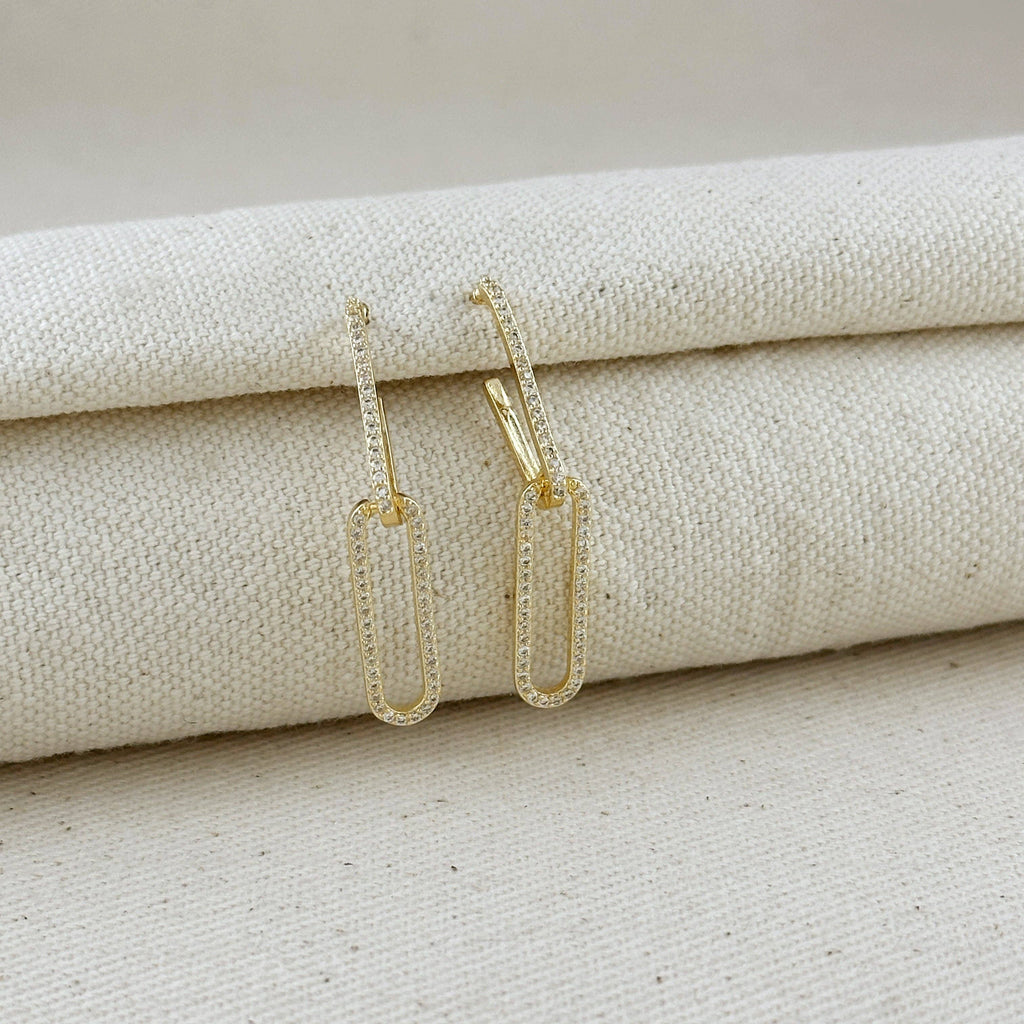 Gold earrings on a textured beige surface