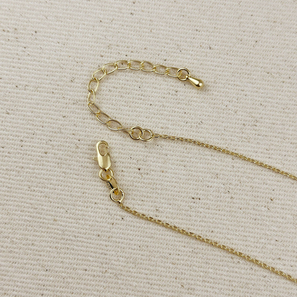 Close-up of a gold-tone chain necklace extender with lobster clasps, laid on a textured beige fabric background.