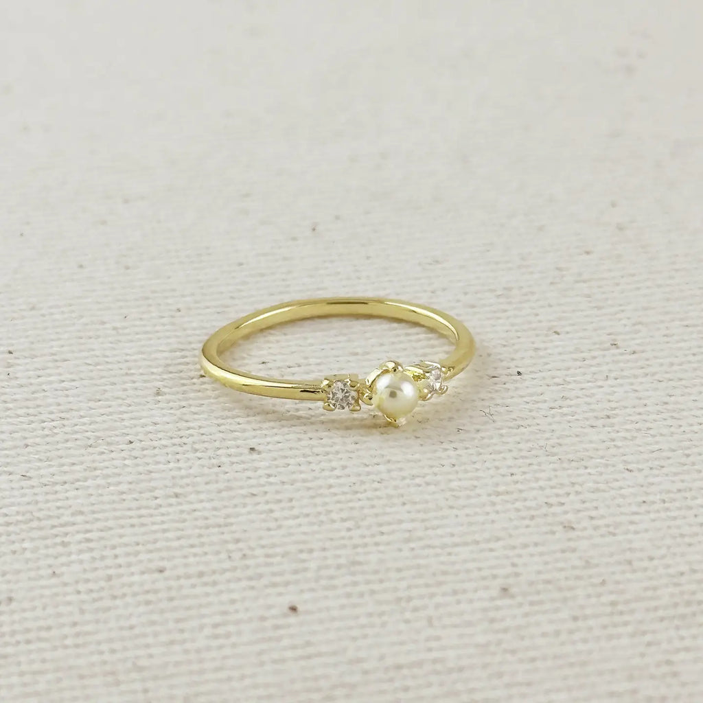 Gold ring with a pearl and small diamonds on a beige fabric background