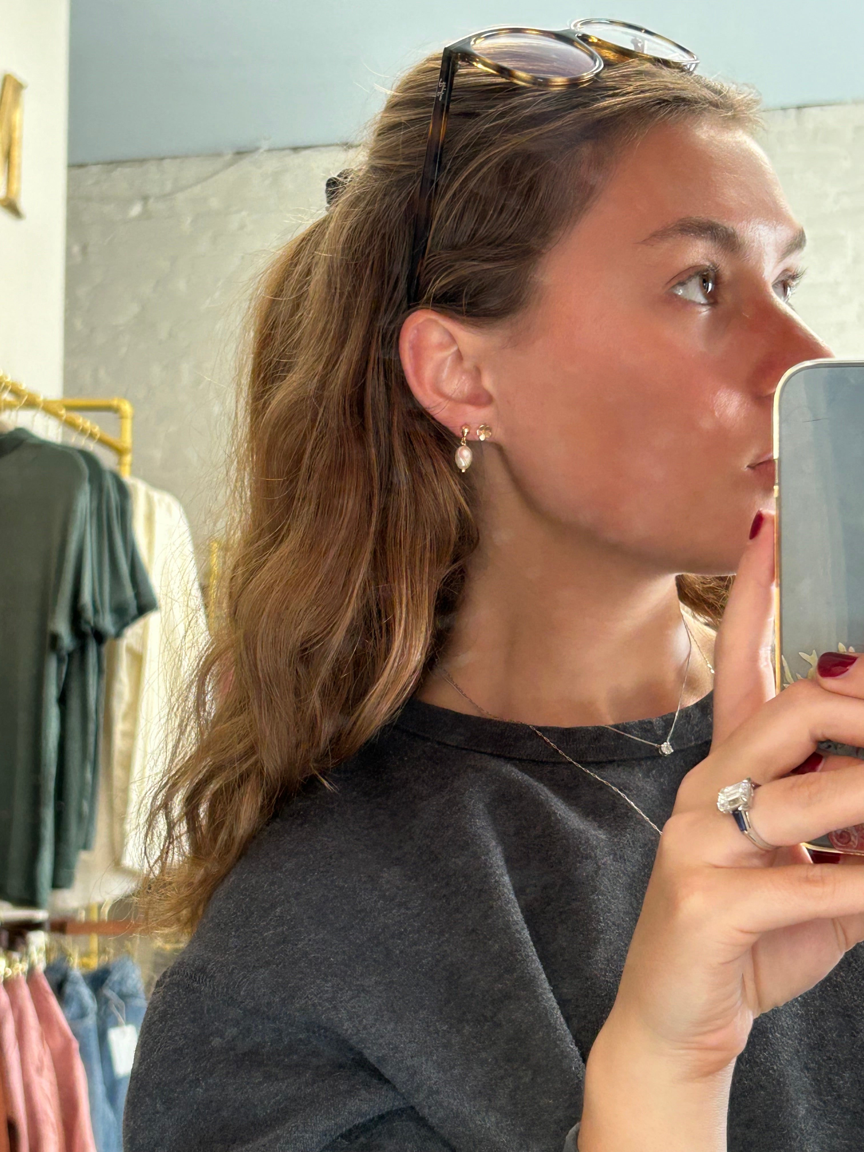 Woman taking a mirror selfie with a smartphone, wearing sunglasses and a gray coat.