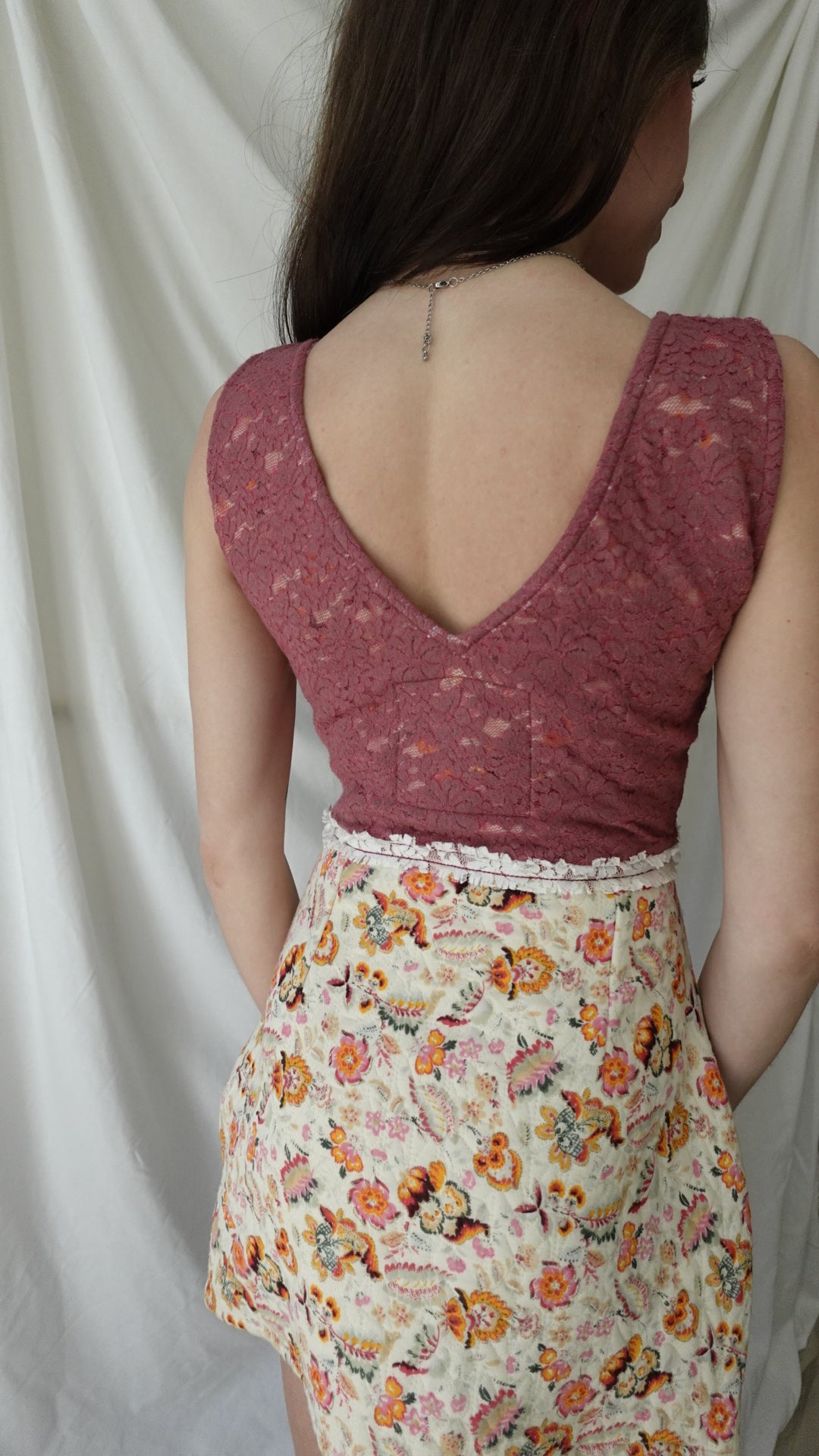 Person wearing a maroon tank top and floral dress on a white background