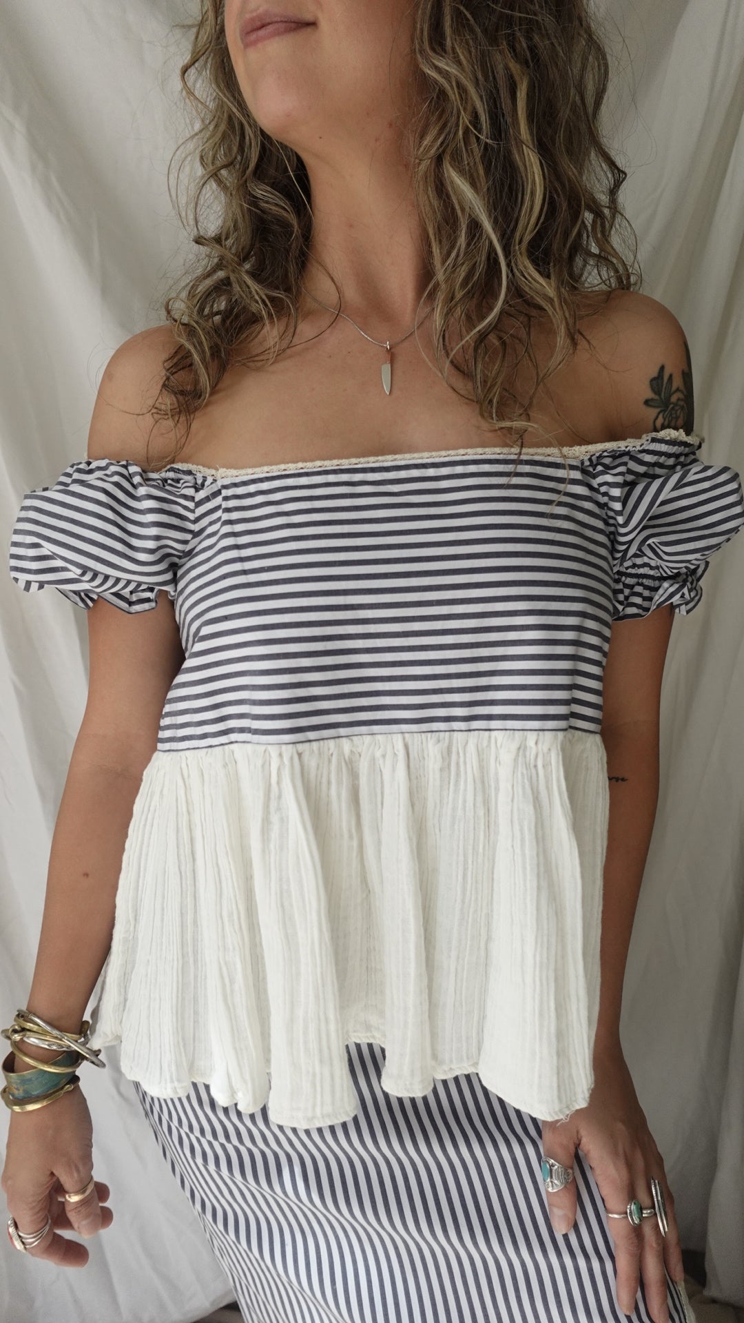Woman wearing a black and white striped dress with pleated details on a white background