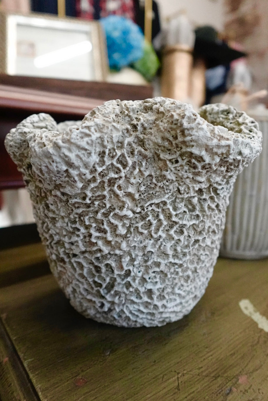 Coral-like textured pot on a wooden surface with blurred background