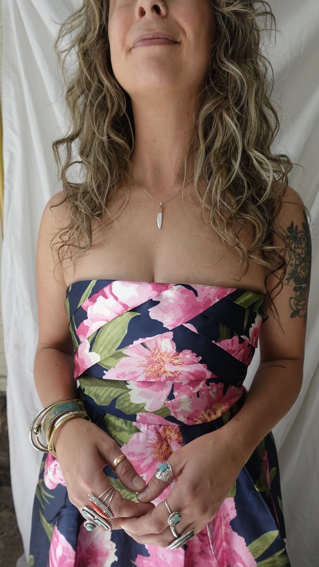 Woman wearing a floral dress with pink flowers and green leaves on a white background