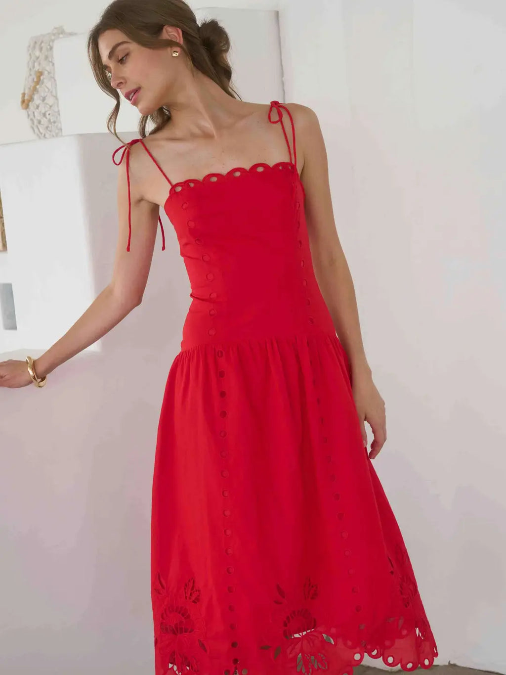 Woman wearing a red dress with lace details against a white background