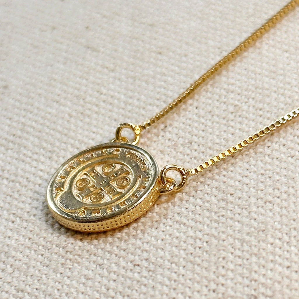 Gold necklace with a round pendant on a beige fabric background