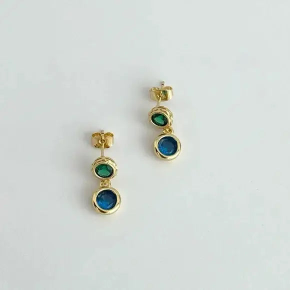 Gold earrings with green and blue gemstones on a light gray background