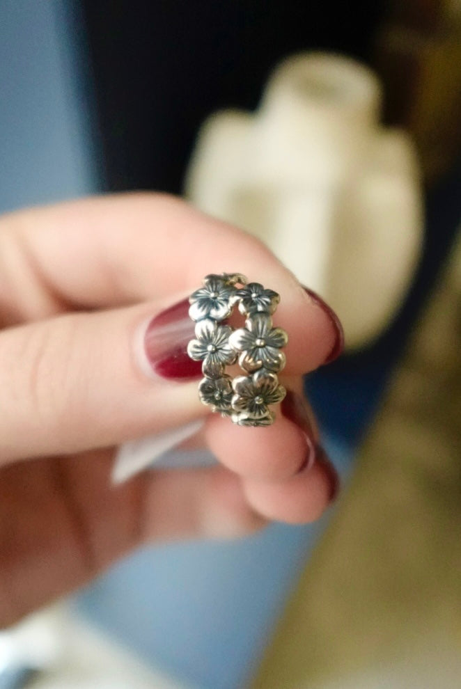 Silver floral ring on a finger with a blurred background