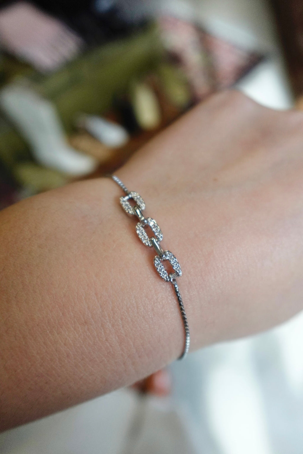 Silver bracelet on a wrist with a blurred background