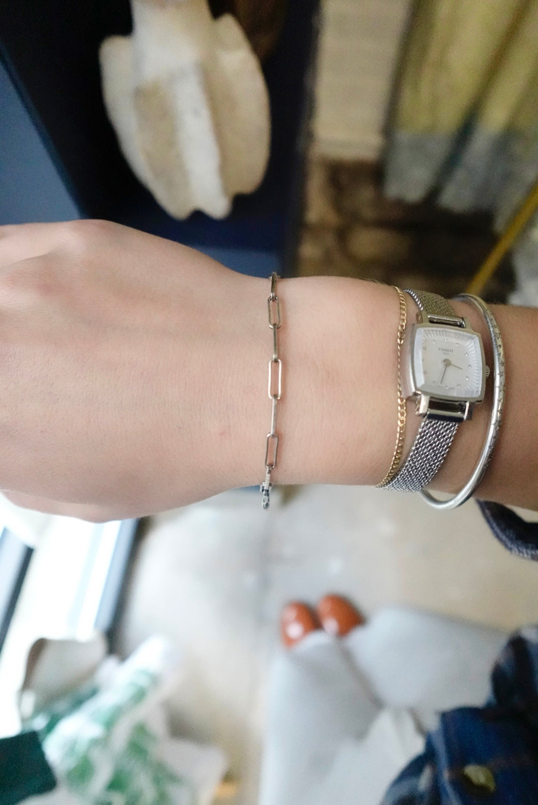 Close-up of a wrist wearing a watch and bracelet with a blurred background
