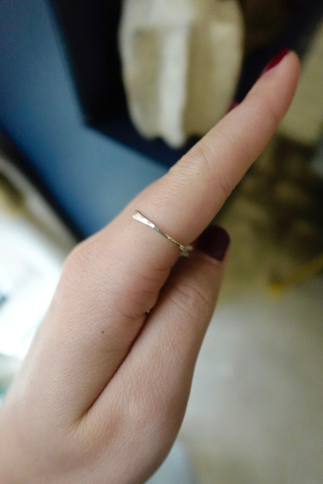 Close-up of a hand wearing a gold ring with a blurred background