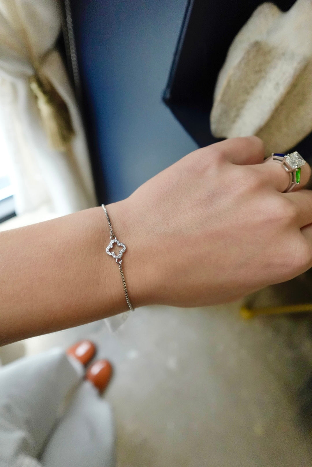 Hand wearing a silver bracelet with a blurred background