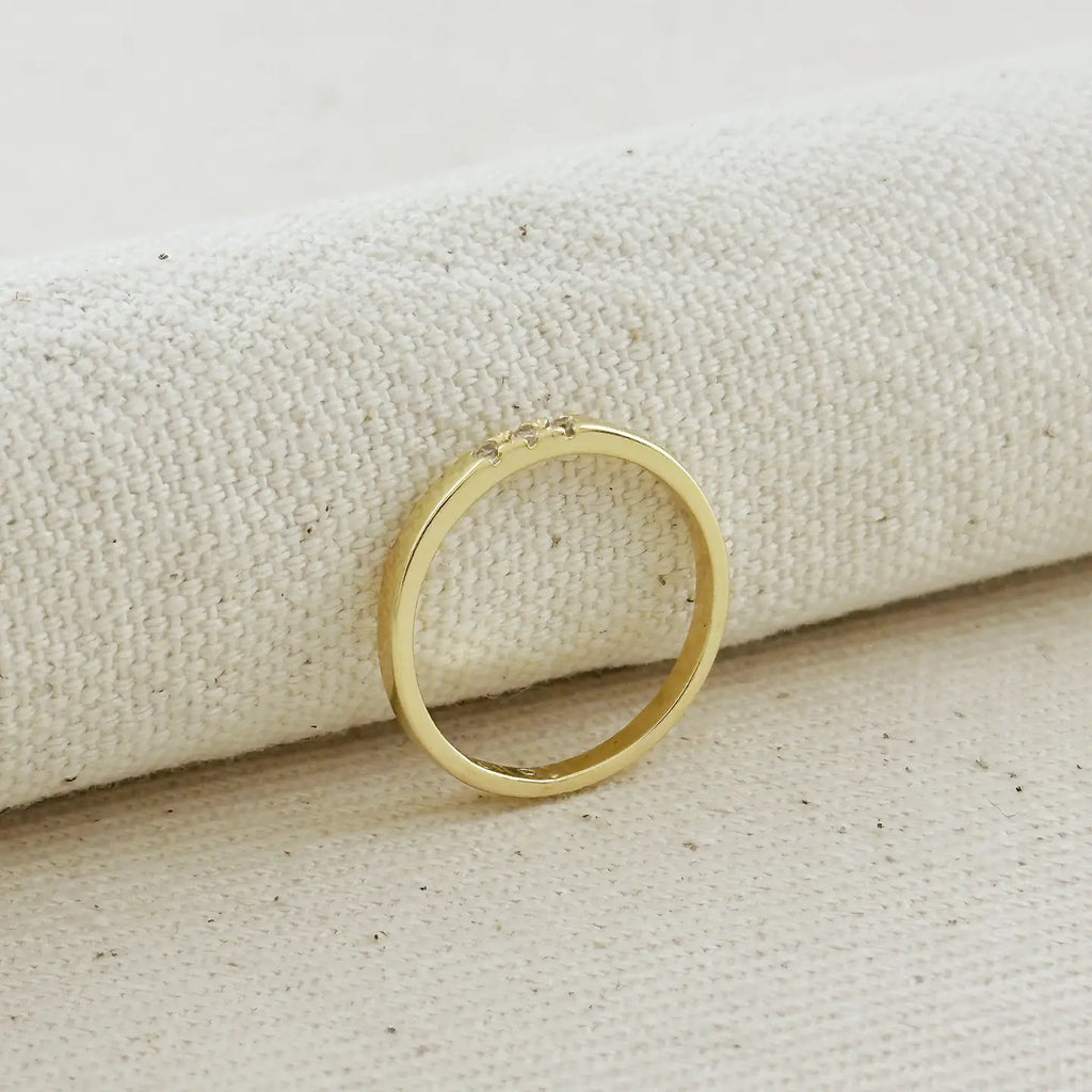 Gold ring on a textured beige surface