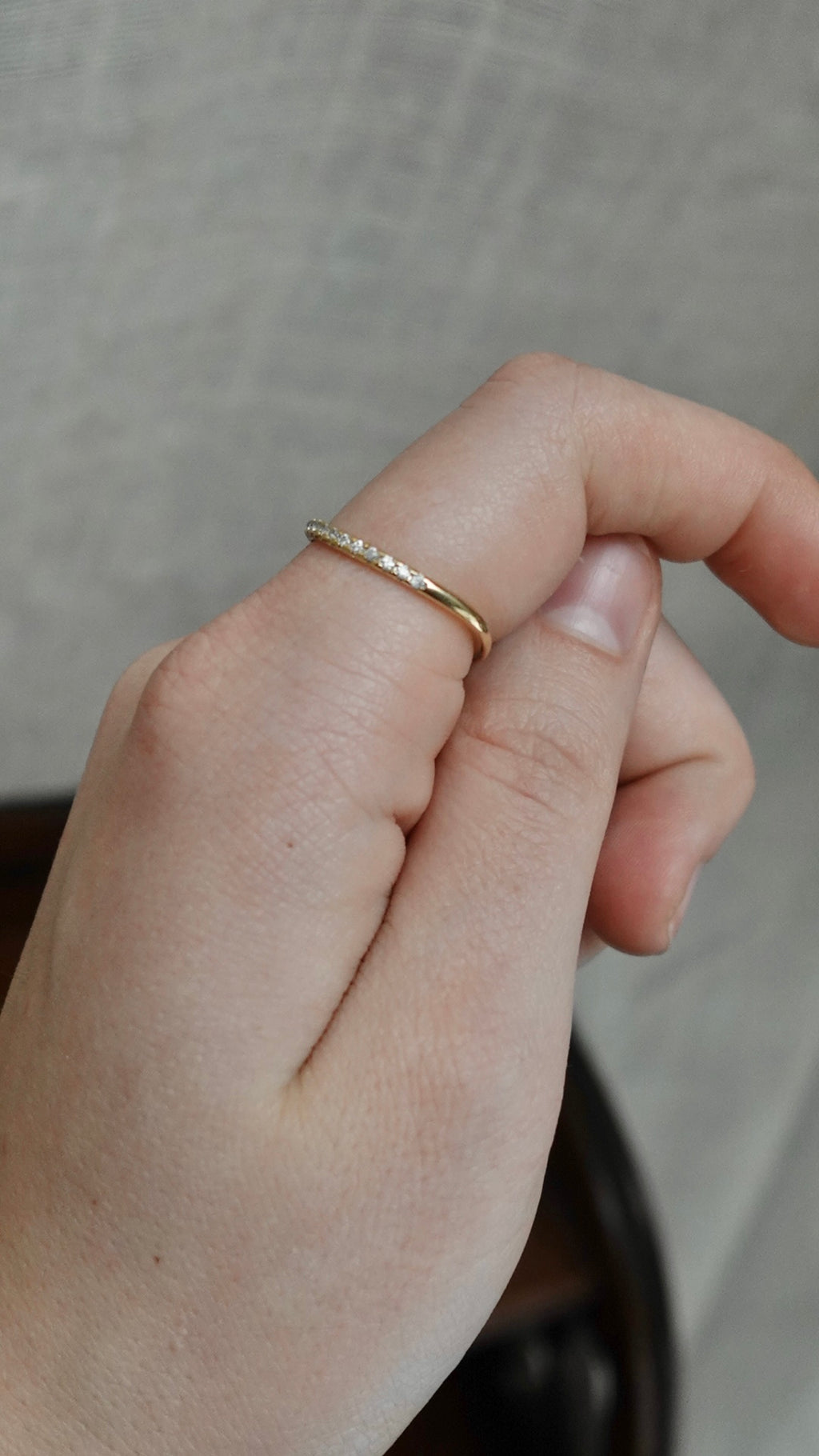Close-up of a hand wearing a gold ring on a neutral background