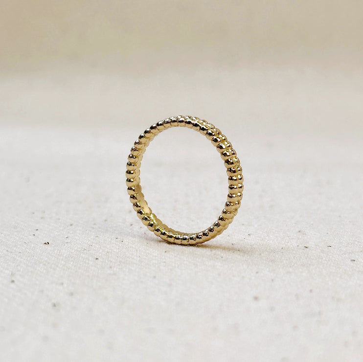 Gold ring with textured band on a light beige background