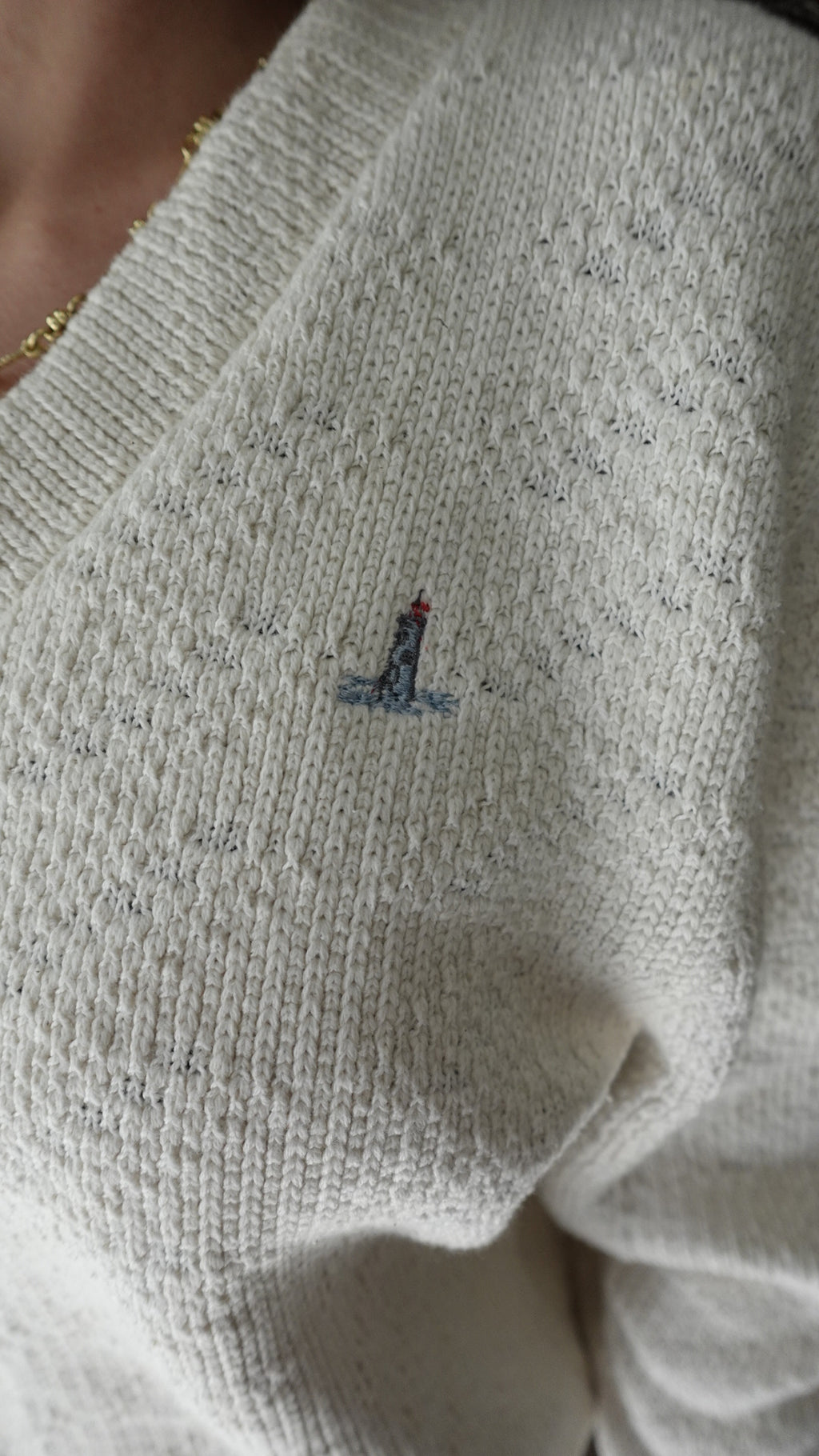 Close-up of a textured fabric with a small embroidered design on a light gray sweater.