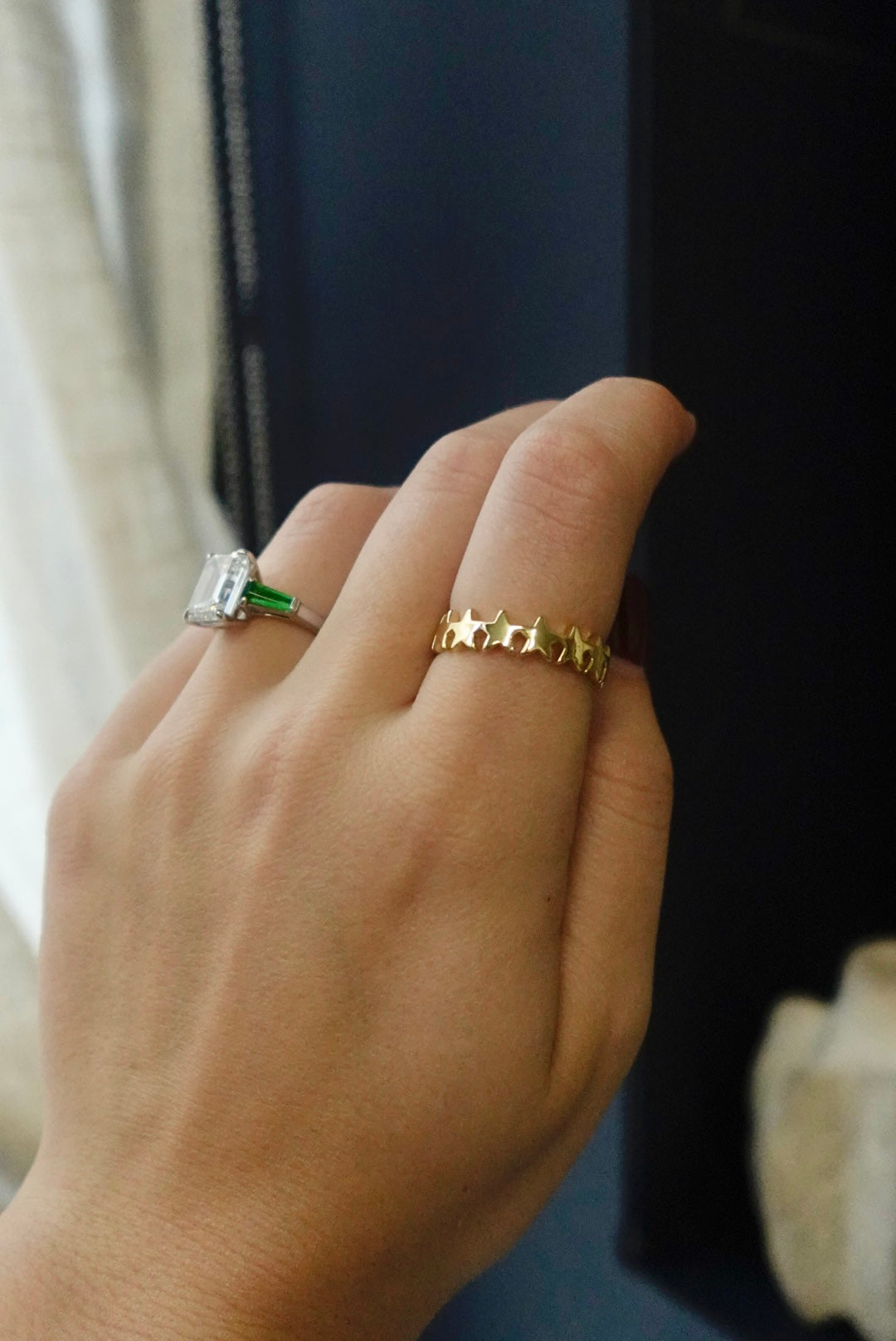 Hand wearing a gold ring with star designs on a dark background