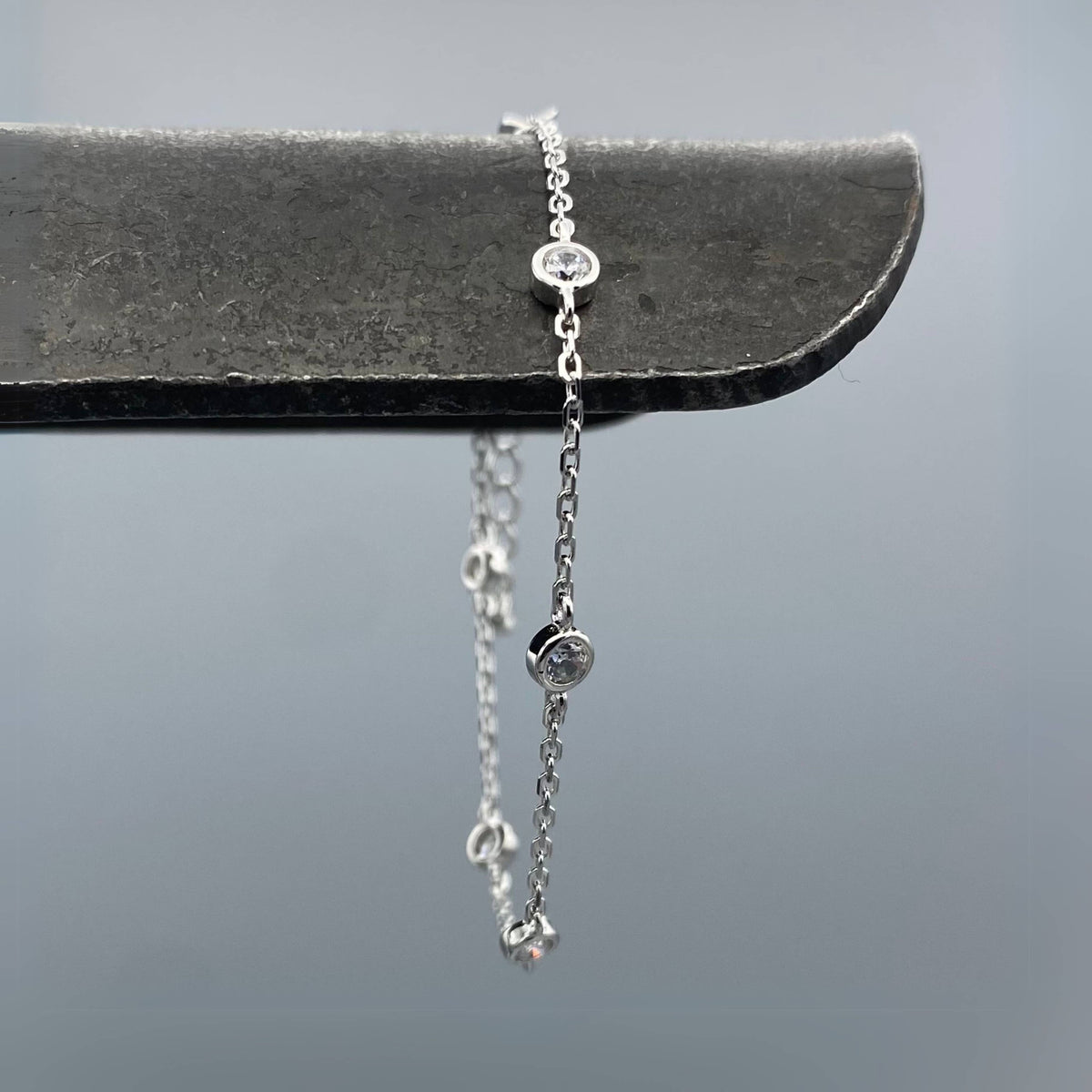 Silver chain bracelet with small round beads on a gray background