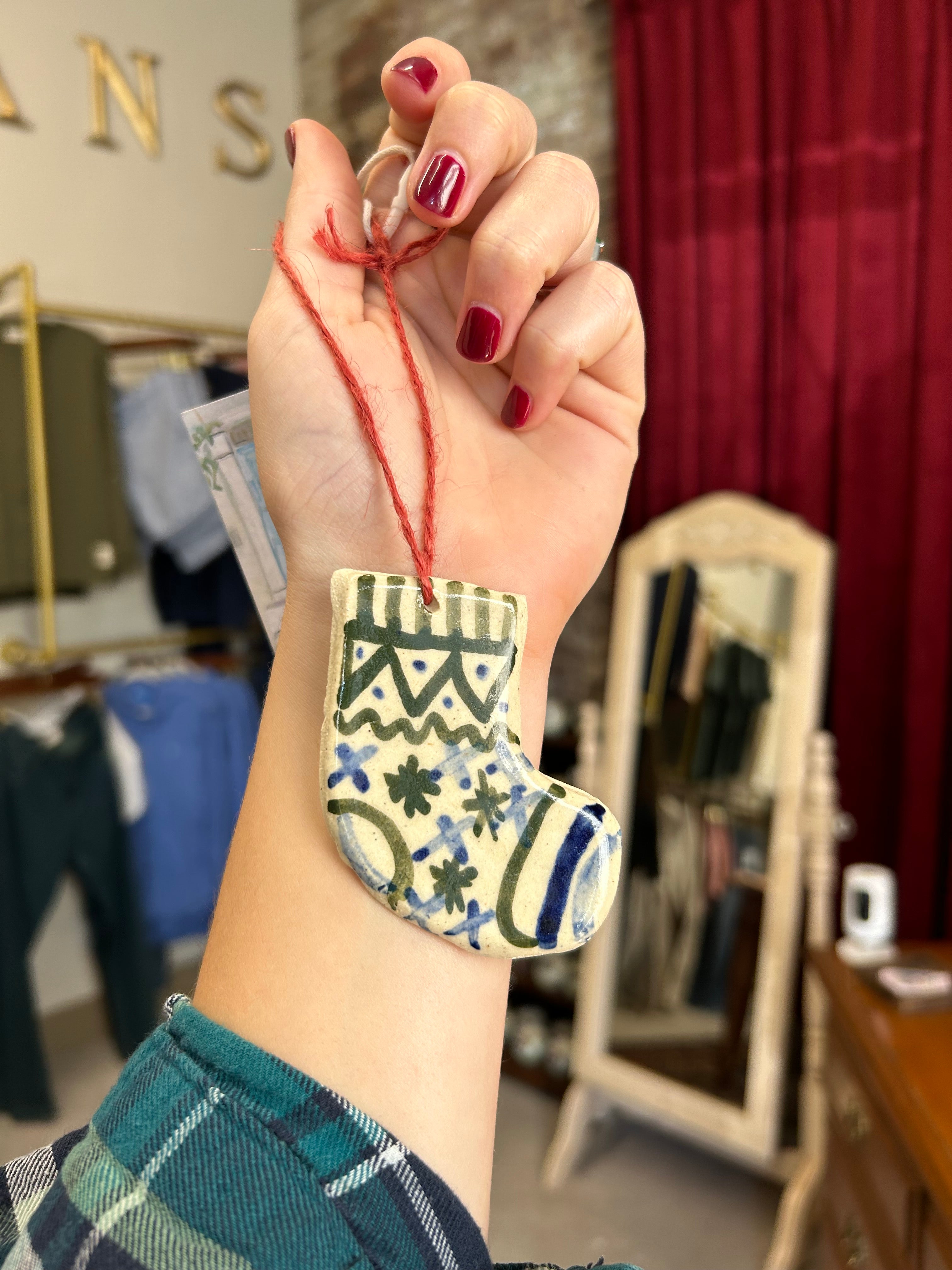 Hand with red nail polish holding a small object, wearing a patterned wristband in an indoor setting.