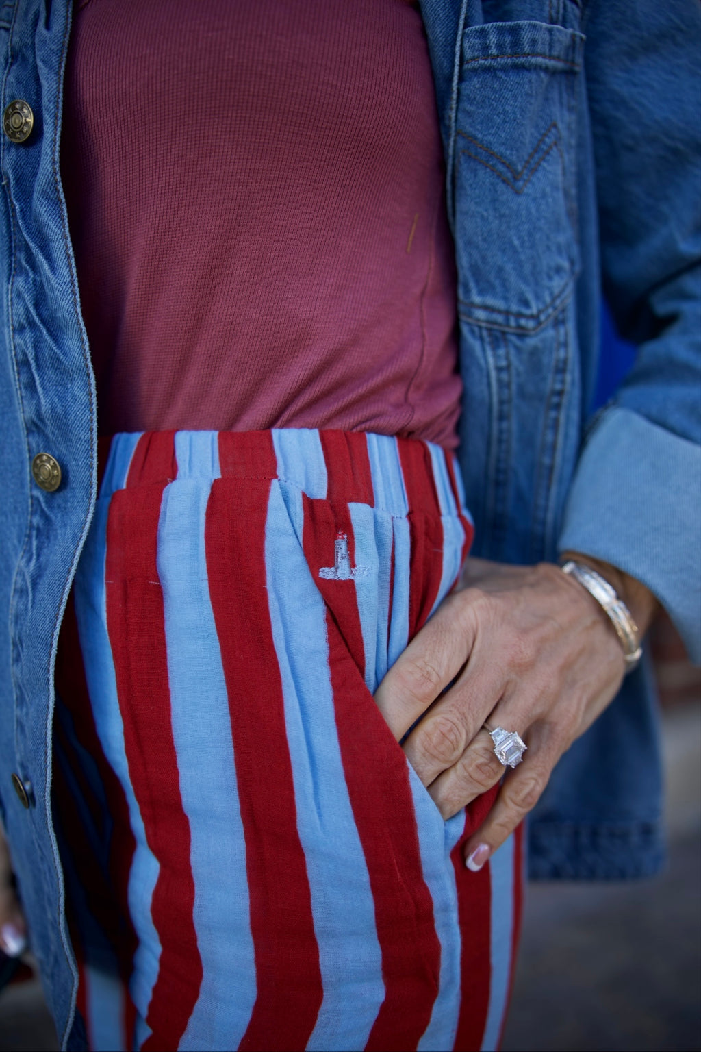 Person wearing a red and blue striped shirt with a denim jacket.
