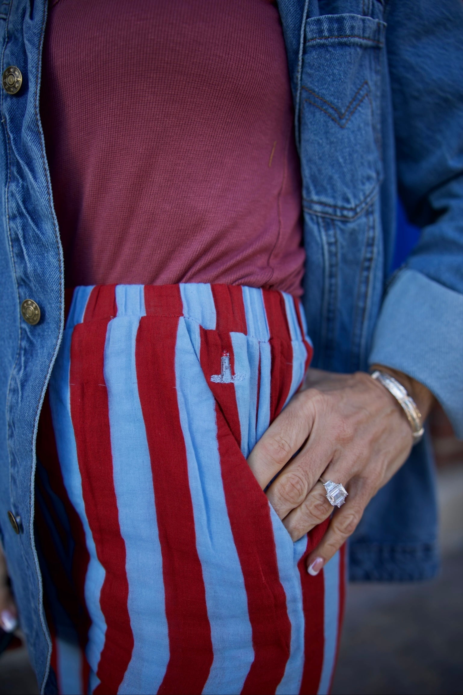 Person wearing a red and blue striped shirt with a denim jacket.