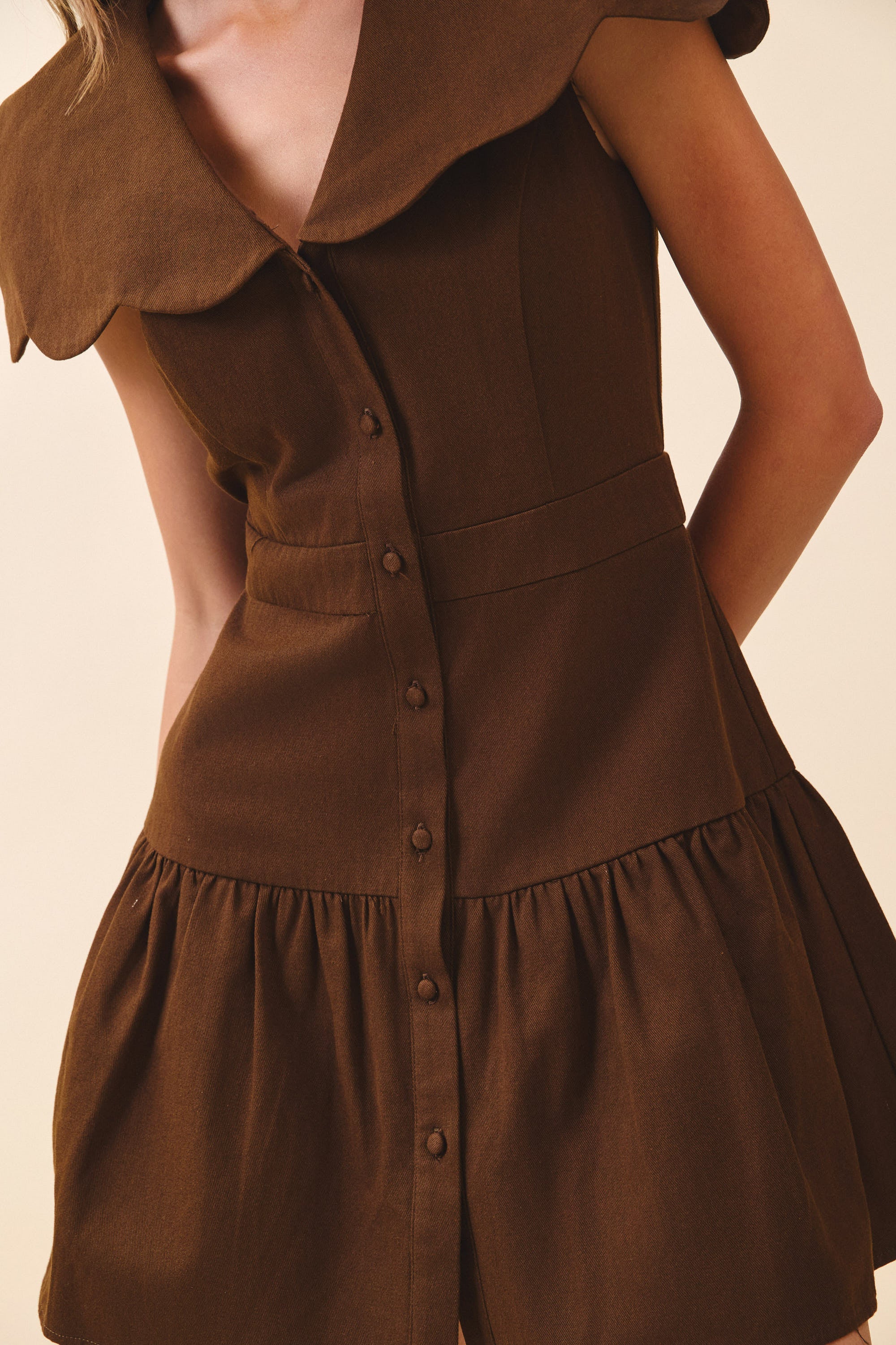 Brown dress with a textured collar on a beige background