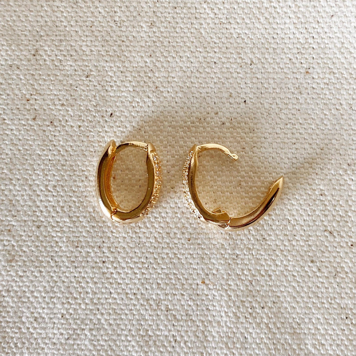 Gold hoop earrings on a textured beige surface