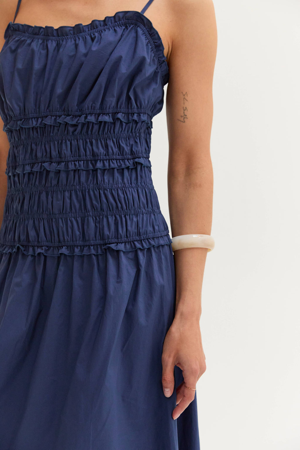 Navy blue dress with ruffled top on a white background