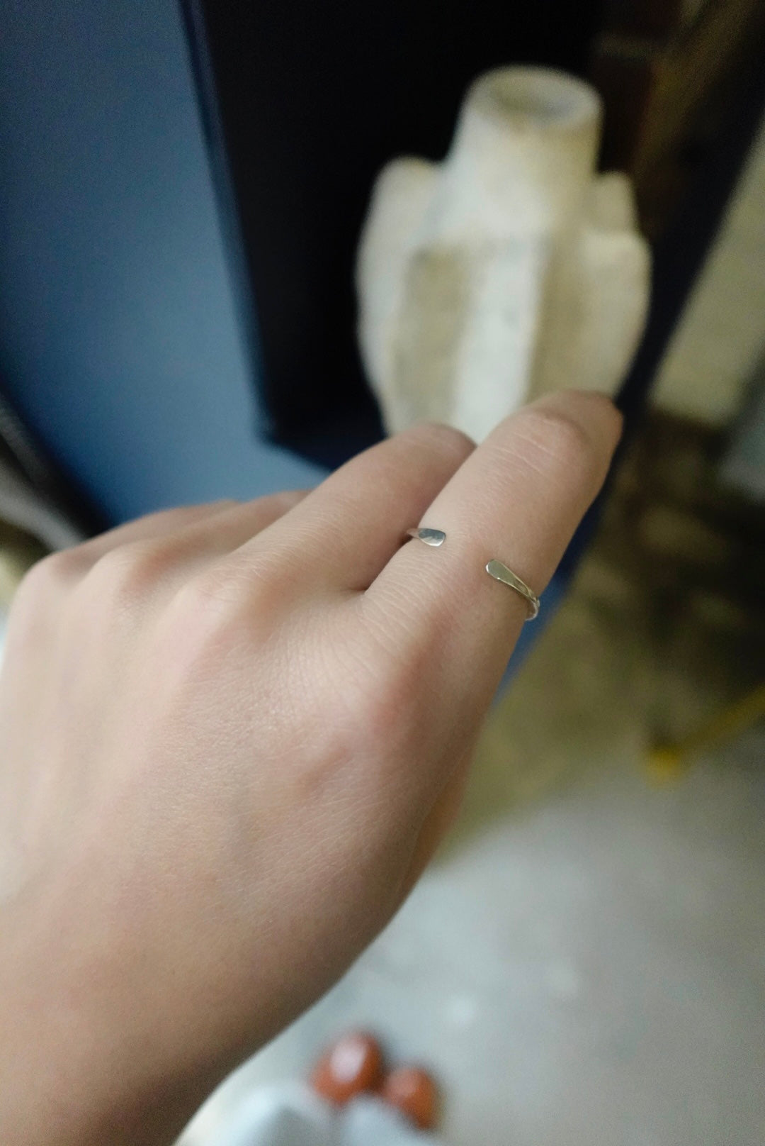 Hand wearing a gold ring with a blurred background