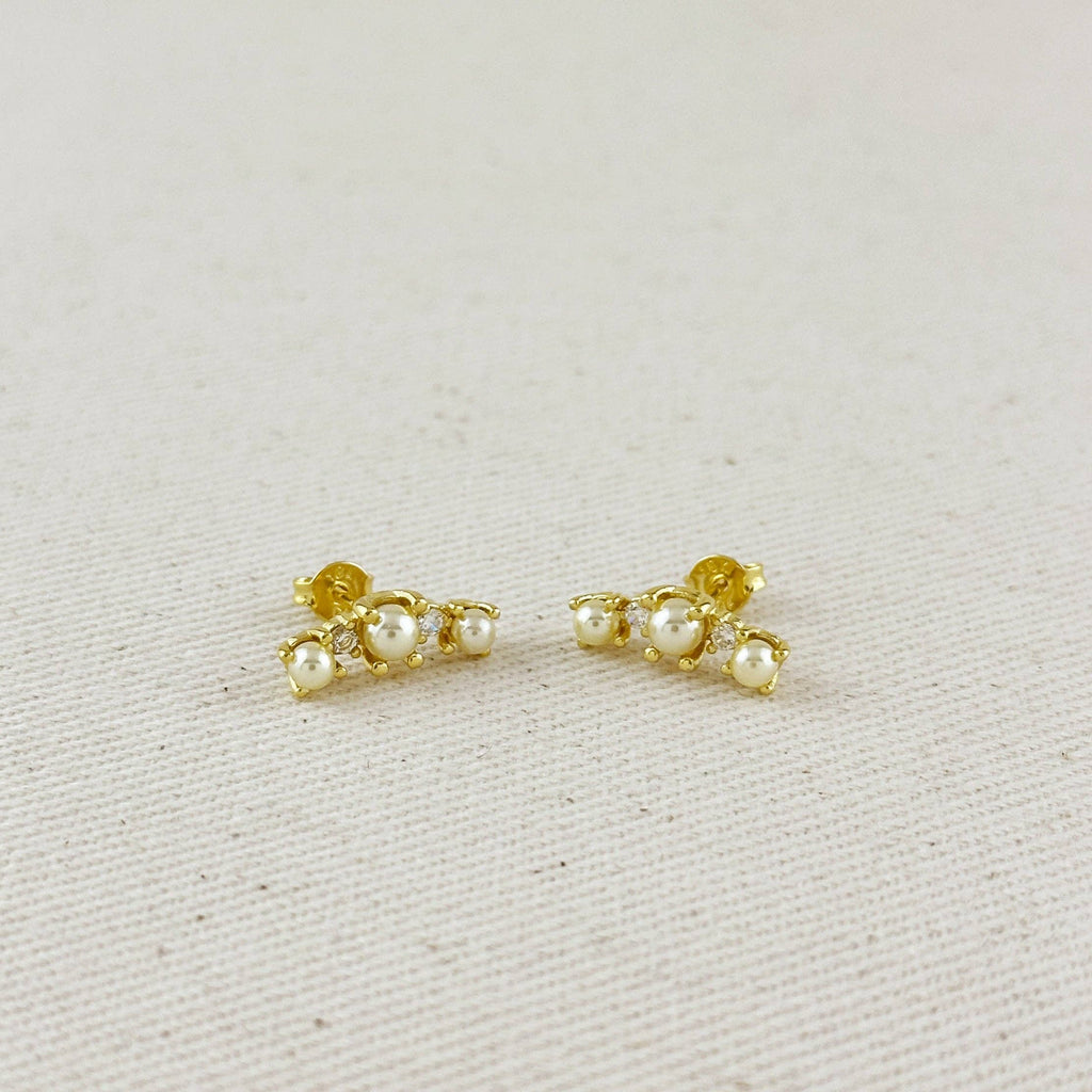 Pair of gold earrings with pearls on a light gray background