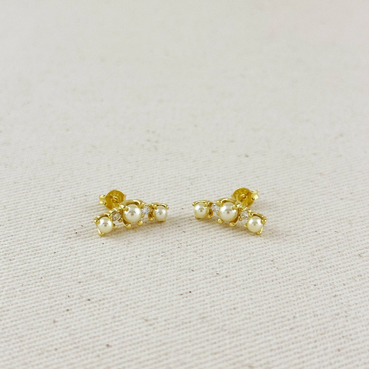 Pair of gold earrings with pearls on a light gray background