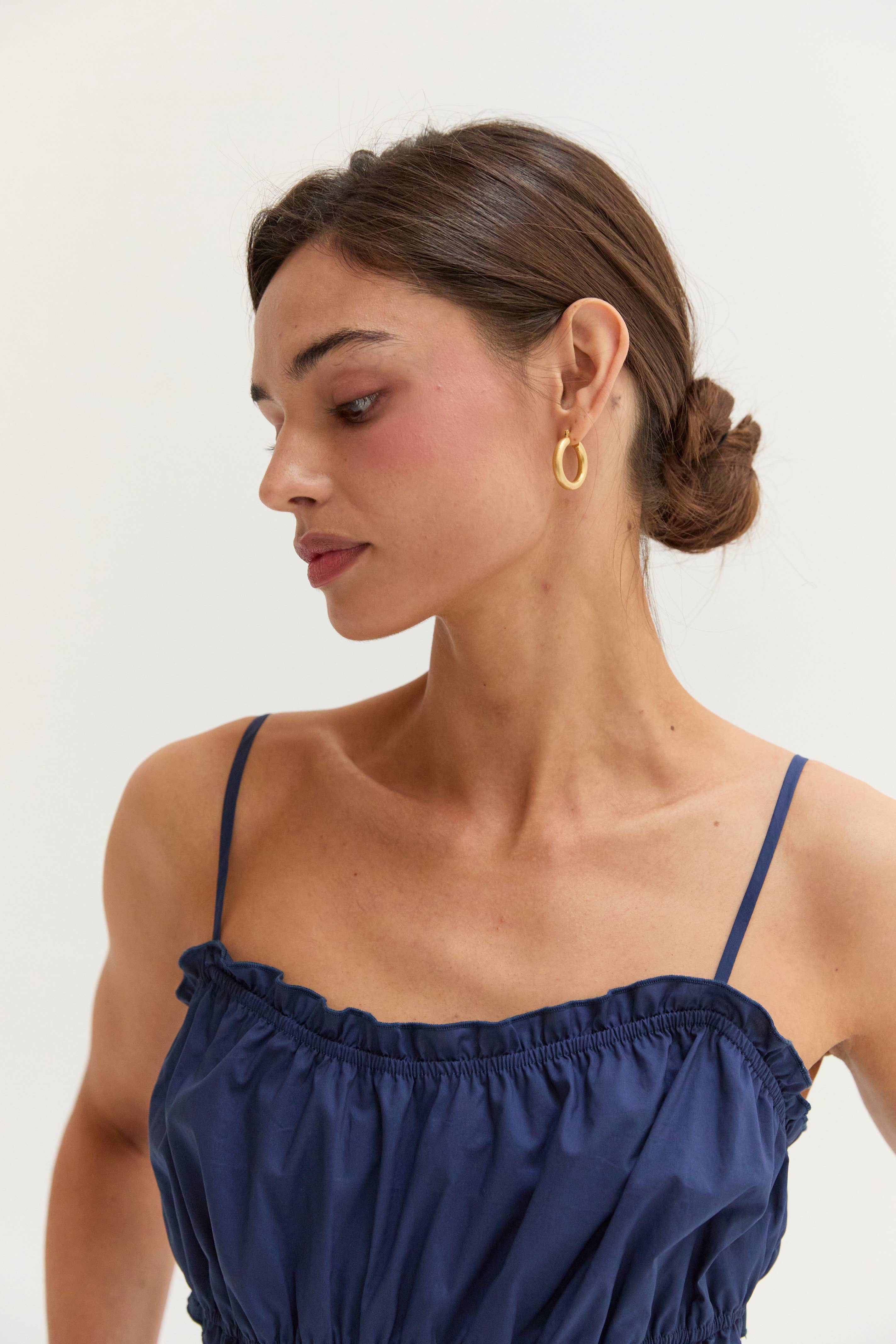 Woman wearing a navy blue top with thin straps against a white background