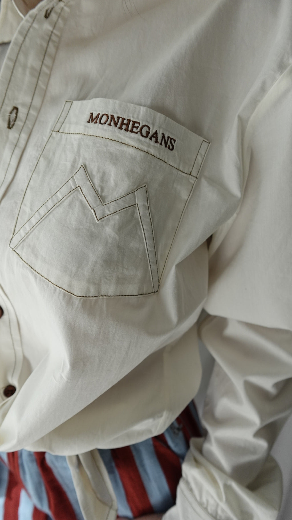 Close-up of a beige jacket with 'MONTECANS' branding on the chest pocket.