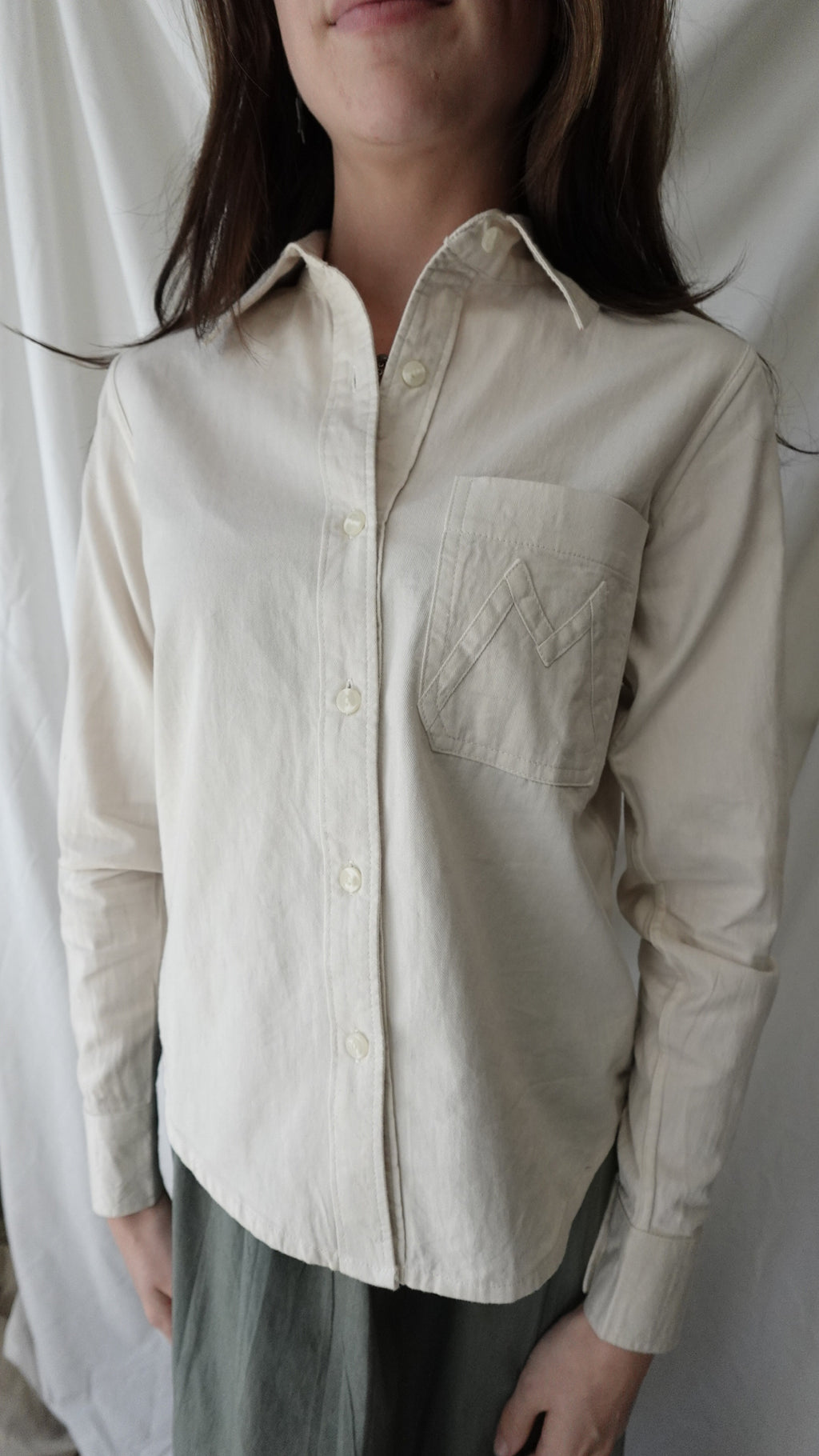 Light-colored shirt being worn by a person on a white background